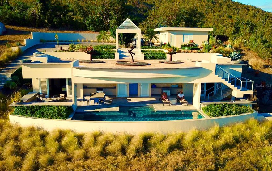 Quinta Jabalí presents a rare opportunity to own an exceptional architectural gem in one of Vieques’ most sought-after locations. Brilliantly designed by renowned architect Stanley Hutchinson, this exceptional estate seamlessly blends modern elegance with natural beauty.

Perched high on a hillside, the home is masterfully positioned to capture sweeping 180-degree views of the Caribbean Sea. The elevated design creates an eagle’s nest effect, offering breathtaking vistas from nearly every angle, while the structure itself is thoughtfully integrated into the terrain — allowing the lush gardens and panoramic views to exist in perfect harmony. This fusion of architecture and landscape makes living here an unforgettable experience.

Set on over two acres of beautifully landscaped grounds, the property is a botanical paradise cultivated over decades by its current owners — both expert landscapers. From the moment you pass through the gated entrance, you're transported into an extraordinary world rarely found elsewhere. The gently curving driveway winds through majestic elephant-sized boulders, rare tropical plants, stately palms, and fruit-bearing trees.

The residence currently serves as a private two bedroom home but was intentionally constructed with the infrastructure to be effortlessly expanded into a four-bedroom layout. The smart floor plan wraps around a serene pool and open-concept outdoor kitchen (grill-ready), ideal for relaxed island living. A detached garage was also designed to be easily converted into an open loft for guests or a studio space.

An expansive grand terrace with a gazebo offers the perfect setting for sunset soirées that transition into starlit gatherings—ideal for entertaining in true Caribbean style.

Located in the exclusive enclave of La Hueca, surrounded by other distinguished estates and adjacent to the Vieques Wildlife Refuge, Quinta Jabalí offers not only privacy and prestige but also proximity to nature’s most stunning landscapes. The property’s carriage-style porte-cochère and timeless design evoke the elegance of a St. Barts estate.

Sustainability and self-sufficiency are key features of this estate, which includes a spacious laundry / storage room, 30 solar panels, tesla powerwalls, two 14,000 gallon cisterns, and eco-conscious infrastructure.

This is not just a home—it’s a legacy property that captures the essence of a luxury island lifestyle.