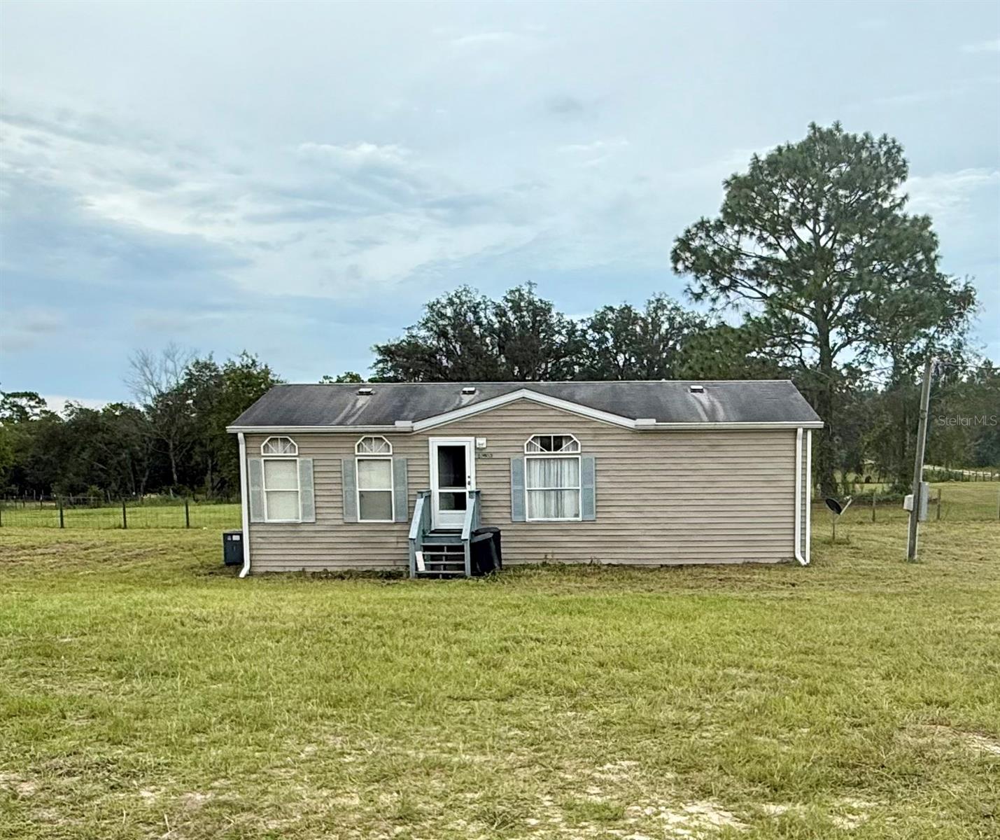 Looking for your first home? This is the one! Nestled on a spacious 1 acre lot, this charming 2 bedroom, 2 bath manufactured home offers the perfect mix of comfort, privacy, and room to grow. Inside you will find an open and inviting layout with a bright living area that flows into the kitchen and dining space. The split bedroom design provides privacy, with a primary with en-suite on one side and a guest bedroom/nursery/office on the other, with an attached bath. Both bedrooms feature generous sized walk in closets. Living room/kitchen/dining room open concept perfect for entertaining. Need more room, the 20 x16 bonus room should be exactly what you are looking for. Step outside and take in all the space this property has to offer. The entire acre is fully fenced, making it ideal for kids, pets, or cultivating your dream garden. There is plenty of room for a playset, fire pit, Rv, boat, or adding a workshop or garage in the future. Whether your just starting out, downsizing, or looking for a little extra space, this property is full of potential. Under 30 minutes to the Gulf of Mexico and 19 minutes to Crystal River. Don't wait, affordable homes on acreage with no HOA don't last long!