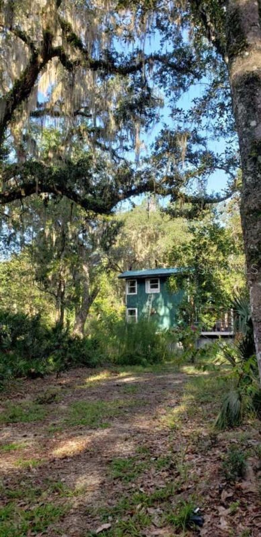 Beautiful two-story cottage on 9.68 acres in historic Cross Creek. Lot is mostly tree covered with old Live Oaks, Magnolias and trails throughout. Original hardwood floors restored, spiral staircase, updated kitchen and bathrooms. Has a top of the line, whole-house well water filtration system, tank-less water heater, added insulation underneath. Quiet, serene living with a screened front porch and open deck, easy access to boat ramps, and close commutes to Gainesville and Ocala. Surrounding lots also tree-covered; Audubon Society owns a large tract to the south.