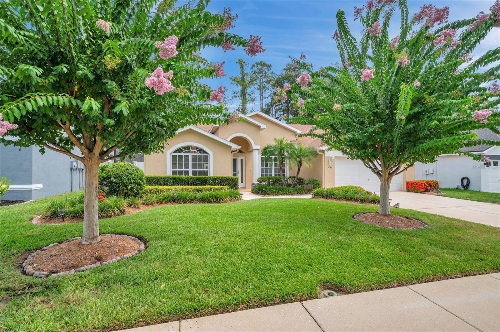 Welcome to Pinewalk—Wesley Chapel’s best-kept secret. You’d never guess this peaceful little community of just 70 homes is right off State Road 54, and once you’re in, it feels like a world of its own. All the homes here are well-kept, and this one stands out with fantastic curb appeal, thanks to its lush landscaping and two beautiful crape myrtle trees welcoming you home.
Inside, it’s clear this place has been loved. It looks and smells like a dream, and with tile floors throughout and a spotless interior, it’s safe to say Mr. and Mrs. Clean definitely live here. The kitchen and bathrooms may not be updated, but they’re so incredibly well-maintained and clean, you might just forget they’re original. The kitchen is bright and functional, with loads of wood cabinetry, Formica countertops, a closet pantry, breakfast bar, and a rolling island that stays. Natural light pours in from a wide window over the sink and an additional eyebrow window up top, and there’s also a cozy breakfast nook with views of the backyard.
The layout features vaulted ceilings throughout most of the home, adding a spacious, open feel. The front bedroom is sunny and inviting, with a walk-in closet and a double window looking out to the yard. The primary suite offers both a 5x6 walk-in closet and a second reach-in closet, an en suite bathroom with a dual vanity, jetted garden tub, and step-in shower, and even a private door (with built-in micro blinds) to the screened and covered patio. The third bedroom is tucked away at the rear of the home, with a longer-than-average reach-in closet, a backyard view, and easy access to the guest bathroom, which features a tub/shower combo and a newer premium Kohler toilet—just like the one in the primary suite.
The living room, dining area, and family room flow beautifully, and both living areas have French doors (with built-in micro blinds) that open to the spacious 12x18 screened patio. The family room features a cozy gas fireplace, perfect for a quiet night in. The laundry room is a dream for anyone who appreciates function, with upper cabinetry, a utility sink, and a window that brings in natural light. Ceiling fans keep the air moving in all three bedrooms, the family room, and the patio.
Important updates include a new roof in 2019, a new AC system with gas heat also in 2019, a gas water heater replaced in 2023, and a water softener and filtration system added in 2022. The owner also added long-lasting 25-year LED flush-mount lighting in the kitchen, living room, and family room.
The backyard is a private retreat with lush grass, a white vinyl fence (with gates on both sides), and room to relax or entertain. And with a leaded glass front door, sidelight window, and two eyebrow windows, the home is flooded with beautiful natural light all day long.
Located just minutes from top-rated schools, shopping, dining, parks, and the ever-popular Epperson Lagoon (under four miles away), and only seven miles from the Tampa Premium Outlets, this home is the definition of “hidden gem.” If you’re looking for a well-maintained, squeaky clean home in a quiet and charming neighborhood—this is the one you’ve been waiting for.