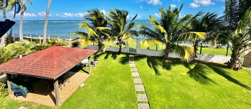 Nestled within the exclusive Espíritu Santo Preserve, this spectacular Swiss chalet–inspired beach residence offers the perfect blend of tropical elegance, privacy, and breathtaking natural beauty. Located just a short stroll from the secluded shores of Las Picuas Beach, the home enjoys sweeping views of the Atlantic Ocean, Puerto Rico’s eastern coastline, and the majestic mountains of El Yunque National Forest.

Set on a generous 975 square meter lot, the property immediately captivates with its expansive manicured front lawn, framed by mature palms and lush tropical landscaping that enhance both privacy and curb appeal. The elevated design, covered terraces, and distinctive dark wood balcony accents reflect its charming chalet character while maximizing ocean breezes and panoramic vistas.

With approximately 2,800 square feet of construction across three levels, the residence was thoughtfully designed with flexibility and future expansion in mind.

First Level:
An inviting living area with half bath and kitchenette opens to a covered outdoor terrace — ideal for entertaining, relaxing in the shade, or creating a separate guest suite. The elevated structure also provides architectural presence and functionality.

Second Level:
The heart of the home features an open-concept family room, dining area, and kitchen seamlessly connected to a spacious ocean-facing terrace. This level also includes two bedrooms with private balconies that share a full bathroom, allowing guests to enjoy both comfort and views.

Third Level:
A loft-style primary suite crowns the residence, offering enhanced privacy, its own balcony with stunning ocean and rainforest views, and an en-suite bath.

The home was originally built with the vision to expand and can be easily converted into a 5-bedroom, 4.5-bath residence, presenting excellent potential for a luxury vacation rental or multigenerational living.

Ideally situated just minutes from Wyndham Grand Rio Mar Golf & Beach Resort, owners have the opportunity to become resort members and enjoy world-class amenities including championship golf courses, tennis and pickleball courts, beach club access, fine dining, bars, and casino entertainment.

The location also offers close proximity to marinas, outlet shopping, stunning beaches, and outdoor adventures, all within approximately 45 minutes drive of Luis Muñoz Marín International Airport.

This is a rare opportunity to own a distinctive ocean-view residence in one of Puerto Rico’s most naturally preserved and desirable coastal communities — ideal as a primary home, vacation retreat, or high-income investment property. Please call now for a private appointment!