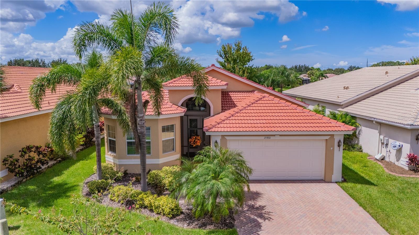 This spectacular Florence model is move-in ready and situated in Valencia Lakes, the greater Tampa Bay area’s premier 55+ resort-style community. Offering 3 bedrooms, 2 bathrooms, and a 2-car garage, this elegant home features a stunning panoramic water view, best enjoyed from the 270-square-foot enclosed Florida room, fully air-conditioned for year-round comfort—an ideal space to relax or entertain.
A new roof was installed in 2023, ensuring peace of mind for years to come. From the moment you arrive, the home's curb appeal stands out with its bay window, barrel tile roof, and brick paver driveway and walkway. Step through the grand 8-foot glass entry door into a foyer with soaring 13-foot ceilings and elegant crown molding, setting the tone for the sophisticated interior that follows. The open-concept great room flows seamlessly into the kitchen and informal dining area, offering a spacious and airy layout framed by serene pond views. The gourmet kitchen is a chef’s dream with a large quartz island, custom shiplap detailing, 42-inch maple cabinets, stainless steel undermount sink, tumble stone marble backsplash, cabinet pantry, under and over cabinet lighting, menu desk, roll-out shelving, pull-out trash, and top-tier stainless steel appliances including a Bosch dishwasher and slide-in range. A generous bay window breakfast nook provides the perfect spot for casual dining with a view. The primary suite is a true retreat featuring a coffered ceiling, luxury vinyl plank flooring, and triple sliders leading directly to the Florida room. Two large custom walk-in closets offer ample storage, and the spa-like bathroom includes dual vanities with quartz countertops, a Roman tub, large walk-in shower with tile surround and built-in seat, upgraded plumbing fixtures, and maple cabinetry—all complemented by custom faux-painted walls. The second bedroom also features LVP flooring, a large window, and is spacious enough for king-size furnishings. The third bedroom or den includes double six-panel doors, a closet and diagonally laid tile flooring, offering flexibility for use as a guest room, office, or hobby space. The second bathroom is thoughtfully appointed with a tub/shower combo, tile surround, quartz countertop with banjo top, and maple cabinets. A separate laundry room includes a washer and dryer, utility sink, and built-in cabinetry for added storage. The home is completely carpet-free, emphasizing its low-maintenance appeal, and boasts numerous upgrades including designer lighting and fans, custom window treatments, plantation shutters, water softener system, screened front entry, extended brick paver patio, sunroom shades, and recent exterior paint. Additional mechanical updates include a newer HVAC system installed in 2018 and a water heater replaced in 2019. Every detail has been considered, making this home truly move-in ready. Valencia Lakes offers a 40,000-square-foot clubhouse, fitness center, resort-style pools, tennis courts, pickleball, walking paths, live entertainment, arts and crafts, and a full calendar of social activities. Don’t miss your opportunity to live in one of the most desirable active adult communities in Florida. Schedule your private showing today and start living the lifestyle you deserve.