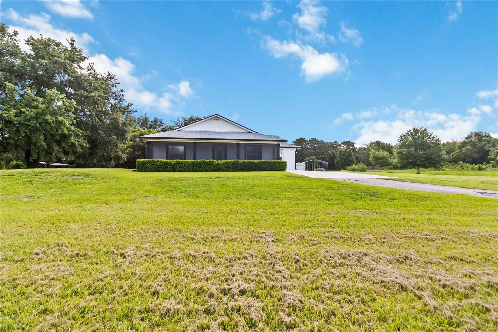 Welcome to this charming 2,543 sq. ft. block home situated on 4.87 acres, offering the perfect balance of peaceful country living and quick access to some of Florida’s most exciting destinations. Set in an area poised for strong future appreciation, this property provides not only a beautiful lifestyle but also an excellent investment opportunity. Step inside to discover a spacious open floor plan connecting the kitchen and living room, creating an inviting space perfect for everyday living and entertaining. The kitchen boasts stainless steel appliances, a farm sink, and plenty of counter space, seamlessly flowing into a large living area and an additional 10’ x 24’ flex room ideal for a playroom, office, or guest room. The expansive primary bedroom features ample closet space and a luxurious en-suite bath with a walk-in shower and dual sinks. Two additional bedrooms each enjoy their own full bathrooms, ensuring comfort and privacy for family and guests. Outside, you’ll find a 40’ x 60’ concrete pad, including a 20’ x 24’ covered section perfect for boat, RV, or outdoor equipment storage, plus a 15’ x 30’ storage shed for added convenience. Just minutes from Disney, Melbourne Beaches, Orlando International Airport, and more, non-HOA community offering freedom and flexibility and Endless possibilities for outdoor fun—from bonfires to family cookouts. Turn this countryside retreat into your dream home and secure a bright future in one of Florida’s most promising areas!
