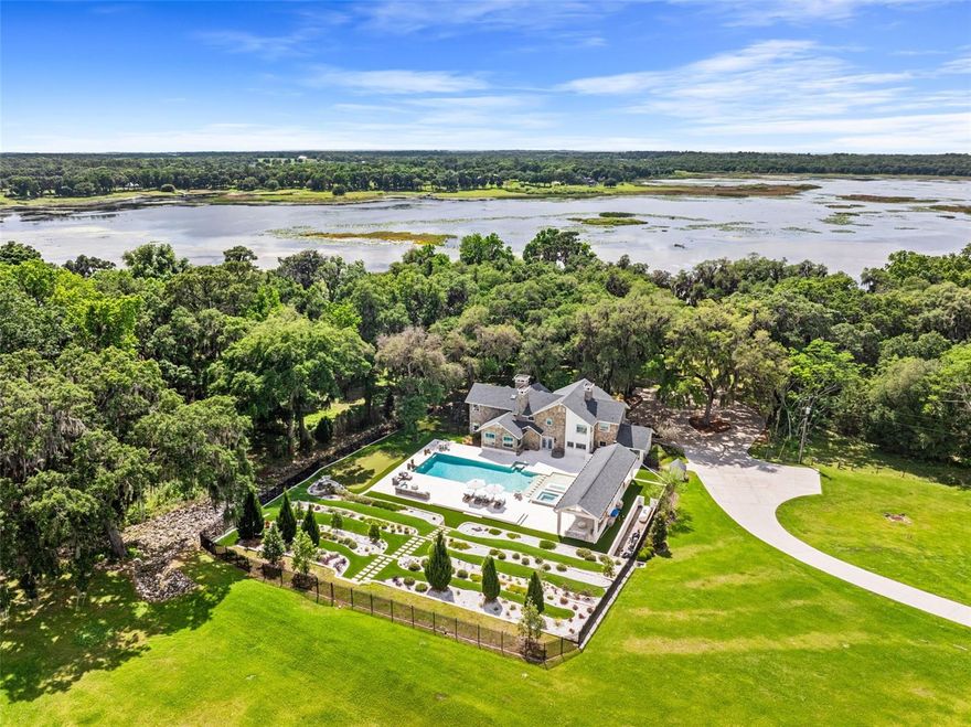 Homes of this caliber and construction are truly once-in-a-lifetime opportunities. Welcome to an extraordinary private lakefront estate in the heart of Central Florida, just a short drive from Tampa and St. Petersburg. Nestled on 10 pristine acres, this meticulously remodeled estate offers nearly 5,000 square feet of refined living space, blending modern luxury with timeless charm. From the moment you arrive at the gated entrance, you are greeted by immaculate landscaping and sweeping views of Lake Hancock that seem to follow you from every window. Whether you’re seeking a grand primary residence or a tranquil retreat, this property is the ultimate escape to paradise. The centerpiece of this estate is its stunning outdoor living space. A resort-style pool and spa, tiered sun pads, and an entertainment pavilion with a covered dining area provide the perfect setting for relaxing or hosting. A putting green, multiple fire features, and a tiered stone backdrop elevate the ambiance, while a separate barbecue area by the lake – complete with seating, a cozy fire pit, and decorative lighting – sets the stage for memorable gatherings. An expansive dock on the lake invites endless kayaking adventures and picturesque sunset views, where the sky is painted with vibrant hues of orange and pink. Inside, this home is nothing short of breathtaking. The eat-in chef’s kitchen features a fireplace, professional-grade Viking appliances, grand quartz countertops, and ample workspace and storage. The living room boasts soaring ceilings, a floor-to-ceiling stone fireplace with a custom mantle, and panoramic windows that showcase the stunning property and lake. The primary suite is a private sanctuary, complete with a stone fireplace, sitting area, oversized designer closets, and a spa-like bathroom that exudes elegance and tranquility. Additional bedrooms and flexible spaces throughout the home offer an abundance of natural light, versatility, and sophisticated architectural design, ensuring comfort and beauty at every turn. No detail has been overlooked in creating this one-of-a-kind estate, from the intricately designed landscaping, 100% poured concrete construction, to the thoughtful integration of luxury amenities. This home is a true masterpiece, designed to inspire awe and provide a haven for relaxation, safety,  and recreation. For more details about the features of this extraordinary property, please ask your agent for the full feature sheet. Don’t miss your chance to make this lakefront dream your reality.