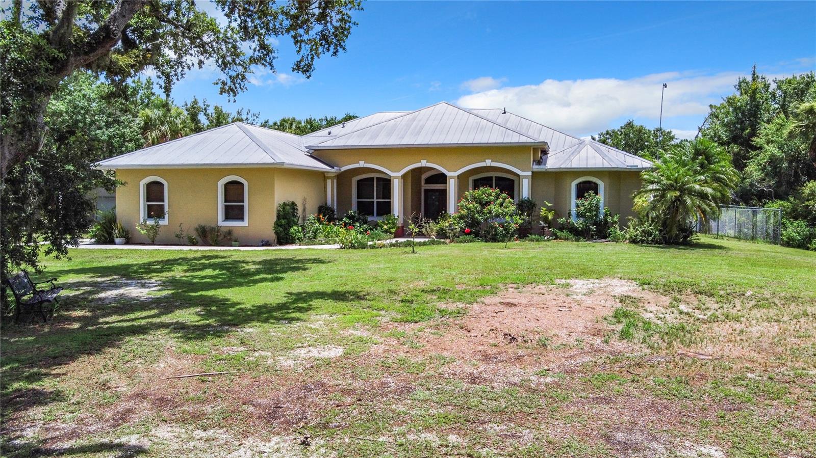 Welcome to 6594 Buckboard St. in North Port Estates—offering 3.1 acres of peaceful Florida country living with no HOA or deed restrictions. This spacious Mediterranean-style estate with a pool and solar power, is priced for a fast sale at $779,000 and won’t last long. Built in 2001 (effective age 2006), this concrete block home offers 3,740 sq ft total, under air, including air conditioned garage. All designed for indoor-outdoor living. Most rooms open to a covered lanai and screened pool area. Features include a metal roof, solar panels for low electric bills, a well (3+ years), septic, propane tank, and hurricane-impact windows in front and back. French doors and custom hurricane shutters secure the lanai, adding storm protection and privacy.
Inside, enjoy 4 bedrooms or (3 plus the office), 2 1/2 baths plus an outdoor/pool shower with hot/cold water, formal living and dining rooms, family room with propane fireplace, tall ceilings, crown molding, and French doors throughout. The kitchen includes Corian countertops, a sunny breakfast nook, new stainless steel stove (2 yrs old), and a brand-new, never-used refrigerator. A new reverse osmosis system is installed in the kitchen. Two newer A/C units (3+ yrs) keep the home comfortable. The air-conditioned garage features built-in cabinets, utility sink, storage closet, and garage door screens.
Additional structures include a 480 sq ft metal outbuilding with ramp and electric (ideal for a business or workshop) and a smaller shed for tools. An 864 sq ft concrete pad with two 60-amp electric panels offers potential for a guest house, office, or business space. The rear pasture is high and dry, ready for horses, livestock, or a barn. A small pond can be stocked for fishing. The property is partially fenced and cross-fenced, with deer, ducks, bunnies, and birds often visiting. Grow chickens, ducks, or even turkeys. Fruit trees include lemon, avocado, and tangerine.
A camper hookup is near the gated entrance, with extra parking for guests and room to host large gatherings or fireworks. The home includes a large laundry room with cabinets, built-in ironing board, and a 2-year-old washer & dryer. The master suite features French doors to the pool, dual walk-in closets, two vanities, a whirlpool tub, and a tiled walk-in shower. The pool bath also includes a shower with hot/cold water access to the lanai.
Located on a quiet street of estate homes near Myakkahatchee Creek Preserve—ideal for hiking, biking, horseback riding, and more. Buckboard Street stays high and dry during the rainy season. Enjoy community events like the annual Go-Kart Parade. The owners have moved out—the home is ready for immediate occupancy.
Minutes from Narramore Park, Butler Park, Warm Mineral Springs, and Wellen Park (home of the Atlanta Braves). Nearby beaches include Englewood (20 min), Venice Beach (20 min), Charlotte Harbor (10 min), and Punta Gorda (20 min). Boca Grande, Sarasota, and Siesta Key are 45 minutes away. This property offers endless potential—perfect for families, homesteaders, or entrepreneurs. Don’t miss this rare opportunity to own your private North Port retreat!
