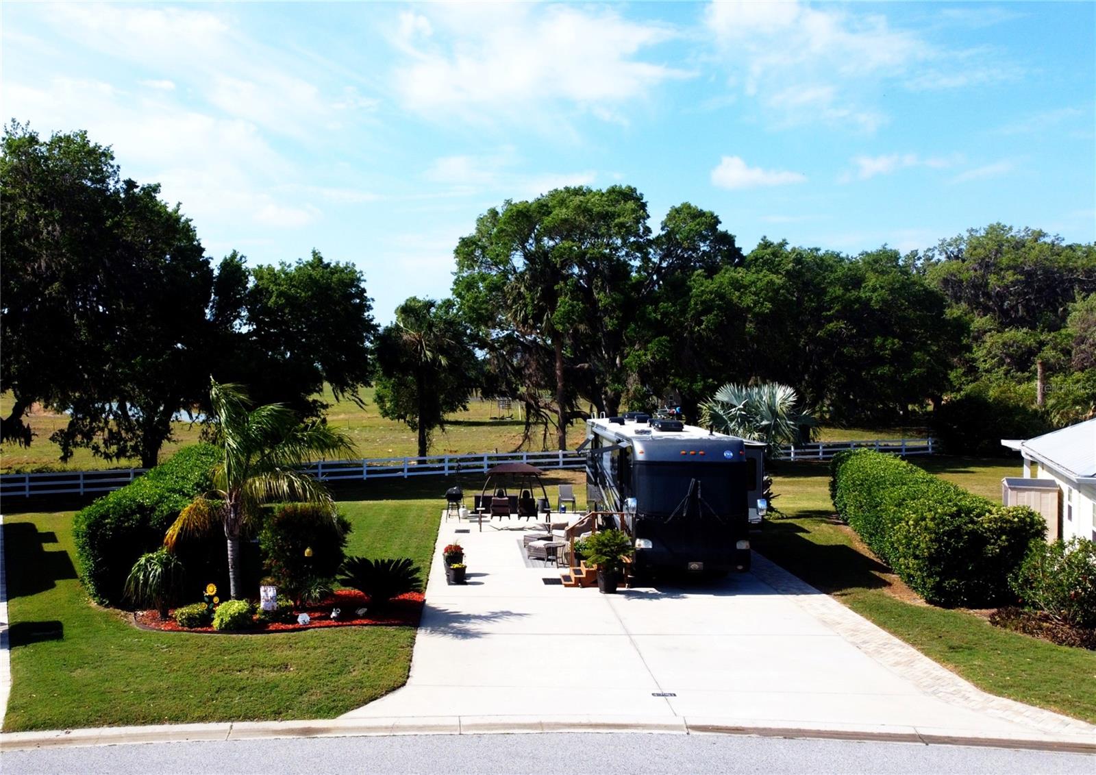 Lot 34 in Florida Grande Motor Coach Resort offers an exceptional opportunity to own an
oversized 6,408 sq. ft. property—over 25% larger than a standard lot. This back-in, north-facing
lot ensures the sun never directly hits your windshield. The windshield view overlooks a serene
green space across the street, while the adjacent cow pasture with majestic southern live oak
trees adds to the stunning natural scenery. Community-owned property at the rear further
enhances the sense of privacy and seclusion.
Meticulously landscaped, this lot features a beautiful Bismarck palm in the back, a lush 7-foot
boundary hedge for added privacy, and a welcoming front yard with another palm and a full
bottlebrush plant that creates an inviting entrance. Pavers line the pedestal side of the pad, adding
both functionality and aesthetic appeal. The expansive 26’x76’ concrete pad is equipped with 50
amp electricity, water, and sewer, making it ready for immediate use. Situated on one of the most
sought-after roads in the resort, this location enjoys minimal traffic, ensuring a peaceful and
relaxing atmosphere.
Florida Grande is a gated Class A and Super C resort in the heart of central Florida, known for its
spacious properties and oversized concrete pads at an affordable price. Ideally located just an
hour from Tampa, Orlando, and Ocala, and within 90 minutes of both Gulf Coast and Atlantic
beaches, it provides easy access to the best of Florida. The area also offers numerous state parks,
natural springs, and manatee viewing locations for those who love outdoor adventures.
Within the resort, residents enjoy a vibrant community and a wealth of amenities. A brand-new
eight-court pickleball complex, a dog park, and a beautiful pool provide opportunities for
recreation, while the 20,000 sq. ft. clubhouse features a fitness center, billiards room, library,
craft room, and gathering spaces for social events. With a full calendar of activities, there’s
always something to do. Don’t miss out on this rare opportunity to own a private, oversized lot in
one of Florida’s premier motorcoach resorts—schedule a showing today!