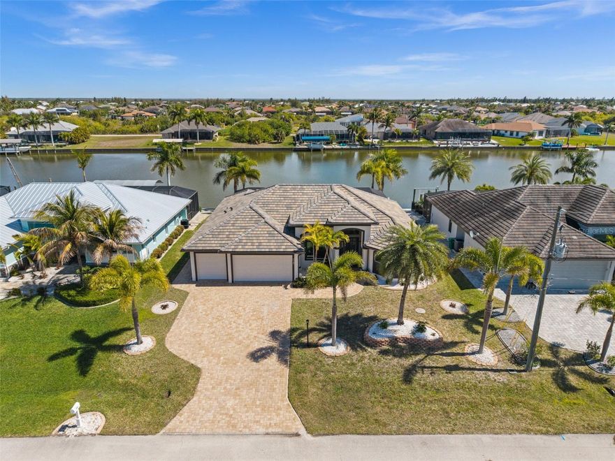 Waterfront Luxury in South Gulf Cove, FL! Welcome to your private slice of paradise in highly esteemed Southwest Florida, perfectly positioned on the scenic Tracy Waterway with direct access to the Gulf of America. This spectacular custom-built 3 bedroom, 2.5 bath, 2,191 square foot waterfront residence delivers the ultimate Florida lifestyle where architectural elegance meets coastal adventure. From the moment you arrive, the thoughtful design impresses with a 3-car garage, coveted tile roof, lush mature landscaping, paver driveway, recessed lighting, and a screened under-roof entry framed by decorative pillars. Step through stunning French doors into a bright, open interior showcasing gorgeous ceramic tile floors, soaring tray ceilings, crown molding, 5.5-inch baseboards, and expansive zero-degree sliders that seamlessly frame the showstopping lanai and custom pool overlooking the tranquil canal. The heart of the home is an entertainer’s dream kitchen featuring an oversized 9.5-foot quartz island with dual-side outlets, custom soft-close wood-faced cabinetry with built-in wine rack, beautiful backsplash, stylish vent hood, updated Samsung appliances, modern pendant lighting, and a spacious closet pantry, all flowing effortlessly into the vibrant dining area with two sliders providing uninterrupted lanai views. A versatile den with decorative half-moon windows and double doors offers the perfect office or guest retreat, while the impressive primary suite boasts private lanai access, tray ceilings, built-in security panel, and two custom walk-in closets leading to a spa-inspired bath filled with natural light, complete with dual shower heads and bench seating, split quartz vanities, and a private water closet. Guest bedrooms offer tall ceilings and spacious closets, with one featuring direct lanai access, and share a beautifully appointed bath with a tiled walk-in shower and quartz vanity. The breathtaking screened lanai is the crown jewel, featuring a uniquely shaped illuminated pool with in-pool table, sun deck and child safety net anchors. The lanai has covered seating with tray ceilings, recessed lighting, double fans, built-in speakers, and an outdoor kitchen with matching quartz countertops, mini fridge, and serving window with hurricane shutters. Beyond, a paver dock lines the canal amid mature tropical landscaping, creating the perfect setting for sunset cruises to the Gulf. Premium features including automatic roll-down hurricane shutters in lanai, impact windows and sliders, security and sprinkler systems, epoxy-finished garage flooring with extra golf cart space, a spacious laundry room with quartz utility sink, and a convenient half bath with pocket door complete this exceptional home—where luxury, security, and effortless indoor-outdoor living come together in true Florida waterfront style.