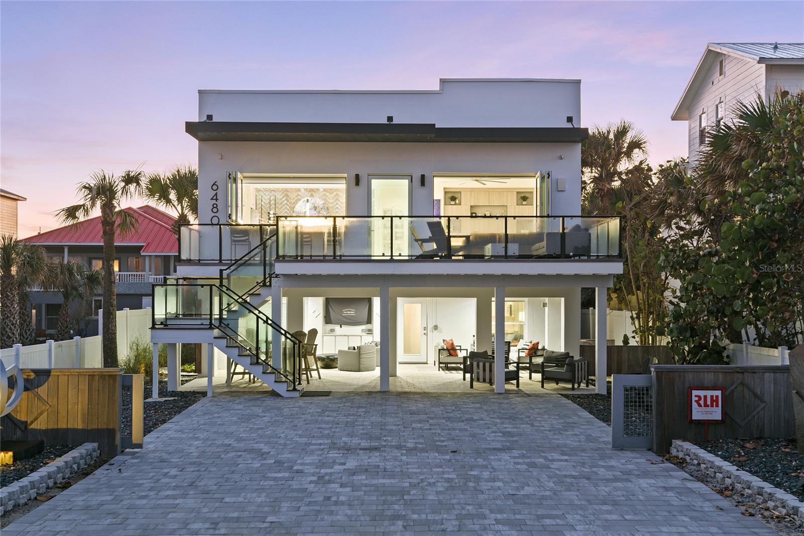 An exclusive oceanfront, gated estate, has been completely reimagined and renovated by renowned RLH Residential. A modern leaning design with clean beach vibes is consistent throughout both residences with state-of-the-art function and materials. This pristine location is in the quiet non-driving beach section, Bethune in New Smyrna Beach known for its sleepy old Florida charm that we all know and love. Sellers combined two properties which resulted in a main house oceanside and guest house on Turtlemound across from the Intercoastal. Sunsets are captured across the intercoastal and the Florida preserve and coupled with incredible sunrises over the ocean. Best of both worlds can be yours on this special barrier island of Florida. The main house renovation in 2022 includes a primary second-story suite and living space on second floor with spacious balcony, and two guest bedrooms, living space and kitchenette on ground floor. The owner's second floor retreat includes a large gathering space with seamless glass sliders opening to second floor deck that allow for panoramic ocean views and blend in the outside. Outdoor living is enhanced with an outdoor fireplace and counter seating from pass-through window from kitchen, makes entertaining a breeze. Designer kitchen includes custom cabinets, Thermador appliances, large center island with seating, dedicated bar and artistic wine wall as the backdrop to a with a full-sized bar. Electric shades allow for ease of privacy while letting soft translucent light filter to spaces. Beach life is easy with spacious primary, spa-influenced bath and incredible closet and storage. First floor of ocean side home features additional bedrooms and living and leads out to the covered walk out patio, great space to shade from the elements and great for weathering summer rains. A 6-7 car-full paver motor court/driveway is also oceanside so parking for friends and family is ample on Atlantic-side drive and two-car garage and parking pad on Turtlemound side. The resort-style center courtyard is where all the fun happens with a private inground fiberglass low-maintenance pool with water slide. Outdoor shower and bathtub for stargazing and taking in the weather that makes Florida desirable. The three-story new construction separate guest house was built in 2023 and rests on Turtlemound Road. The first floor features two-car garage and tons of storage for pool and beach fun. Second and third floors each are mini suites, both floors with living spaces, efficiency kitchens and three additional bedrooms in guest house. This six-bedroom 4.5-bath house can accommodate a large family comfortably. These owners have meticulously designed these spaces, and every detail accounted for. This is an incredible opportunity to own an oceanfront estate that has been built and renovated to stand the test of time. Inquire for a detailed list of upgrades of this unique offering and for a private showing.