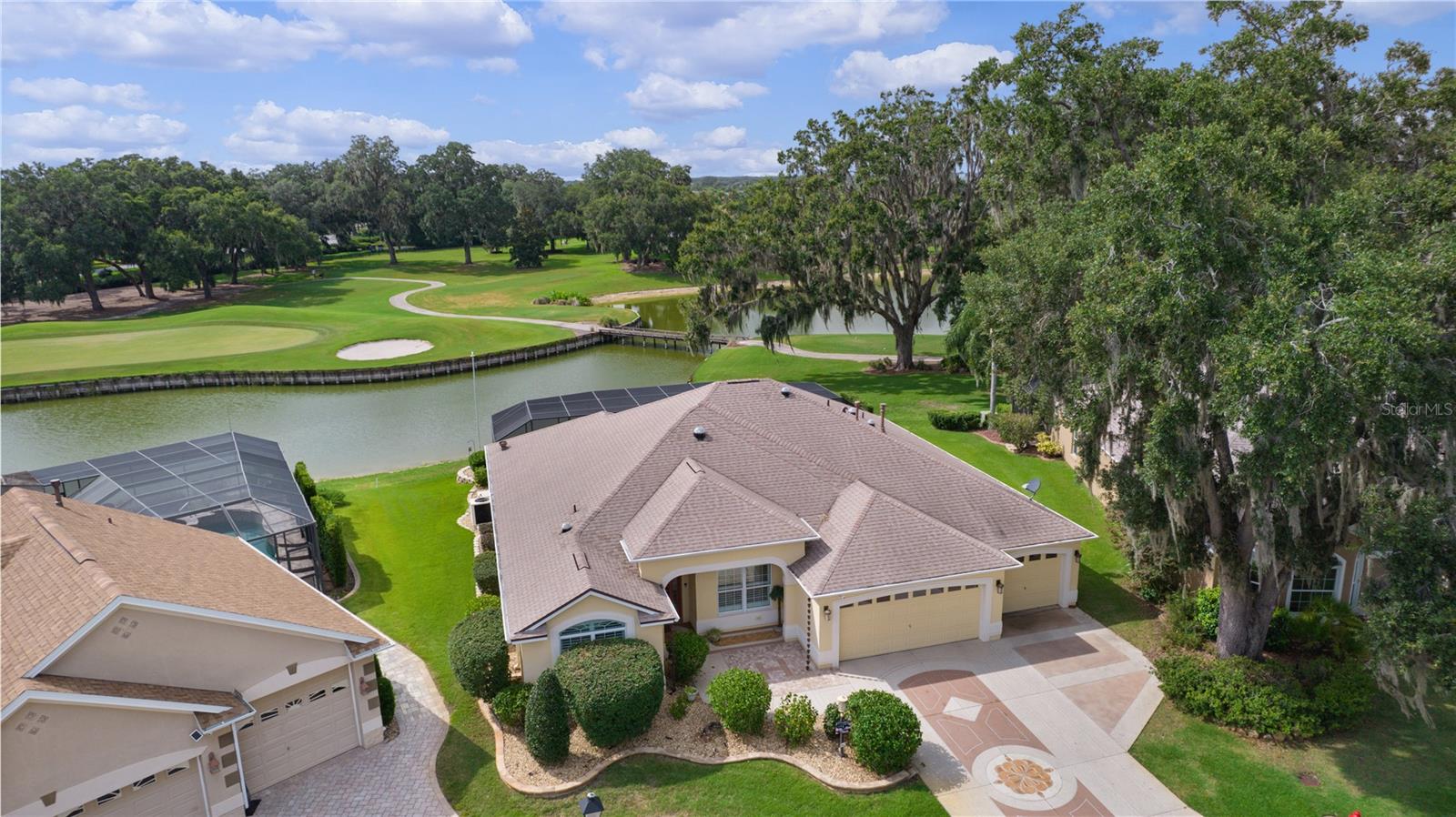 One or more photo(s) has been virtually staged. UP TO 5-CAR GARAGE!
Stunning GARDENIA Model by LAKE SUMTER LANDING in VIRGINIA TRACE – WATER & GOLF COURSE FRONT!
Welcome to this showstopper GARDENIA model, located in the highly sought-after Village of VIRGINIA TRACE. This beautiful home offers the perfect blend of luxury, comfort, and outdoor living—all nestled on the third hole of the Virginia Course with water and golf course frontage. The golf cart path is across the water, providing additional privacy.
Key Features:
Spacious Layout:
3 Bedrooms (note: no closet in the front bedroom) and 2 Bathrooms
Elegant Interior:
PLANTATION SHUTTERS throughout,
CROWN MOULDING,
VAULTED CEILINGS (NO POPCORN!), and
No carpet—just gorgeous TILE and LUXURY VINYL PLANK (LVP) FLOORING,
Chef’s Kitchen:
ONE-LEVEL QUARTZ COUNTERTOPS with matching QUARTZ BACKSPLASH,
STAINLESS STEEL APPLIANCES (LG, except BOSCH dishwasher)
GAS RANGE,
CABINET PULLOUTS, and
DIMMABLE ABOVE- AND UNDER-CABINET LIGHTING.
Luxurious Primary Suite & Bathrooms:
ONYX SHOWERS and GRANITE COUNTERS in both bathrooms,
SOLAR TUBES in both bathrooms with BUILT-IN NIGHT LIGHTS, and
UPGRADED FIXTURES.
Outdoor Living & Entertainment:
SALTWATER POOL with WATERFALL,
Built-in sit-in TABLE/BAR,
STUNNING LANDSCAPING and OVERSIZED BIRDCAGE,
SECOND KITCHEN in the lanai with BOSCH GAS RANGE—perfect for entertaining, and
DECORATIVE TEXTURED DRIVEWAY AND WALKWAY.
Garage & Mechanical Features:
Outstanding 3-CAR GARAGE with EPOXY-COATED FLOORS,
MINI-SPLIT UNIT for climate control,
Garage fits UP TO 5 CARS (third bay fits three vehicles back-to-back),
NEWER ROOF with LEAF GUARDS,
NEWER BREAKER PANEL,
TANKLESS HOT WATER HEATER,
WHOLE-HOME GENERAC GENERATOR, and
5 SOLAR TUBES (two with night lights).
Additional Luxuries:
BUILT-IN DESKS in the primary and front bedrooms,
SLIDING SCREEN DOOR at the front entry,
ROUNDED BULLNOSE CORNERS,
NEWER HIGH-END LIGHTING & CEILING FANS, and
GORGEOUS LANDSCAPING.
This exceptional home offers modern upgrades, resort-style outdoor living, and a prime location in Virginia Trace—just 1.3 miles to Lake Sumter Landing.