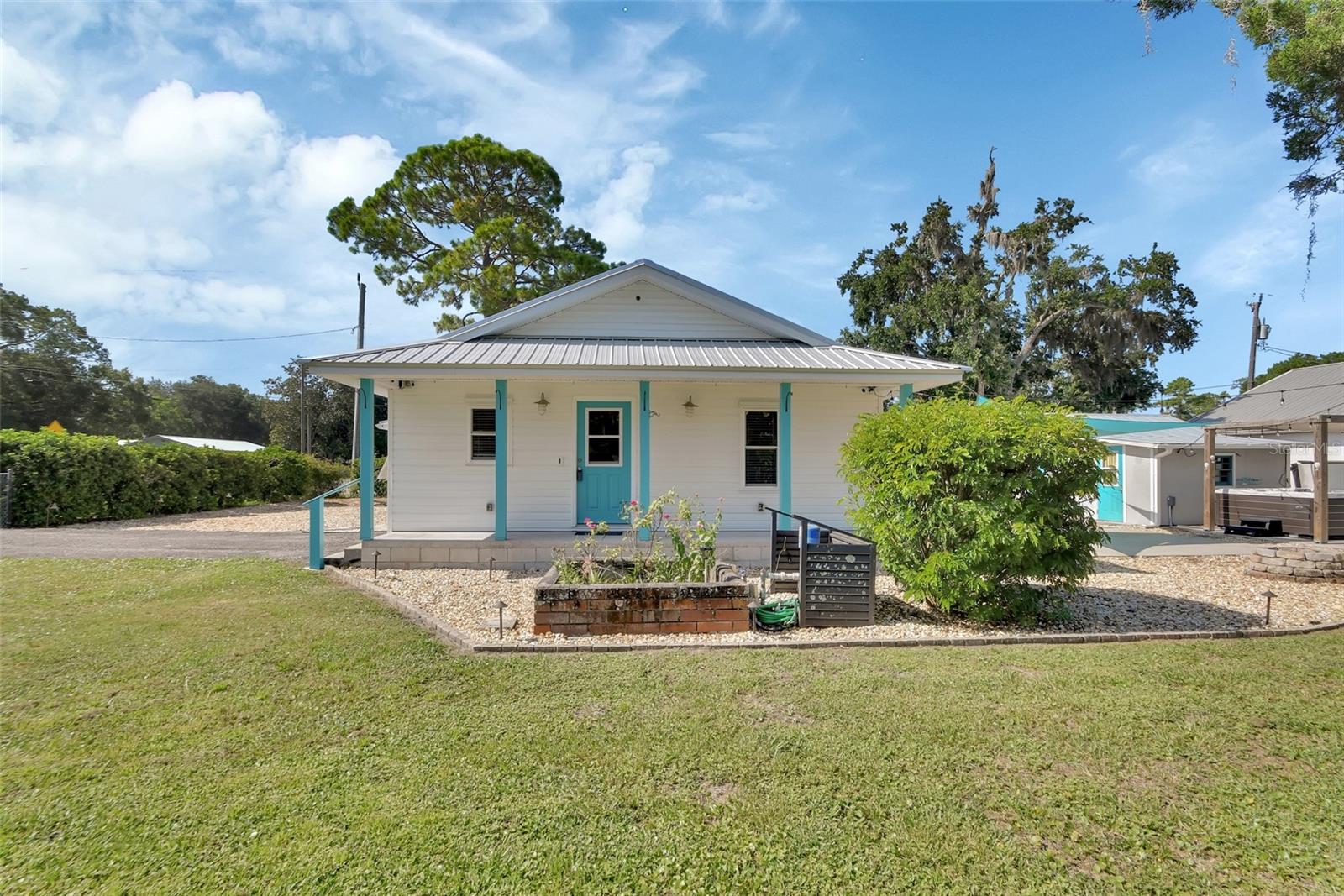 One or more photo(s) has been virtually staged. Located just minutes from downtown New Smyrna Beach, this home is perfect for anyone looking to experience all the area has in store. Situated on over half an acre and fully fenced, the property features a complete RV port with 30-amp service and an extra high roof, a detached garage, and multiple storage sheds, there’s room for all your toys! A circular driveway ensures safe and easy access to and from Pioneer Trail, while an additional gated entry on Parker Street offers even more convenience. The garage is no ordinary affair. This unique space offers endless opportunities with a high volume ceiling and elevated storage areas. Tinker, sculpt, paint, sand, or repair anything you can think of. The front porch and raised garden bed are perfect for your favorite plants, while the firepit and massive jacuzzi set the stage for entertaining. The spacious yard gives you endless room to play, relax, or create, and you already have a head start with avocado, lime, orange, and tangerine trees. Partial lot landscaping makes yard maintenance simple without sacrificing space. Metal roof installed in November of 2020! Step into the mudroom with a utility sink for easy cleanup, then into a bright, spacious kitchen featuring solid wood cabinetry, quartz countertops, a breakfast bar, and a central island with a prep sink. Natural light floods the space, making it a joy to cook and gather. An enclosed glass porch allows for al fresco dining without the nuisance of heat or bugs, and the cozy den with a fireplace is perfect for any season. The primary bedroom offers three closets for effortless organization, plus a charming powder room for added convenience. The second bedroom makes a great guest space or craft room, and the main bathroom includes an upgraded shower with bench seating and a built-in magnifying mirror. With two detached storage rooms and a large garage, your possibilities are endless: think air-conditioned craft room, workshop, or simply ample storage. There’s even a private outdoor shower for easy beach cleanup and a secondary screened-in porch for even more entertainment space. Versatile, spacious, and ready for whatever you have in mind, this property is the perfect place to call home.