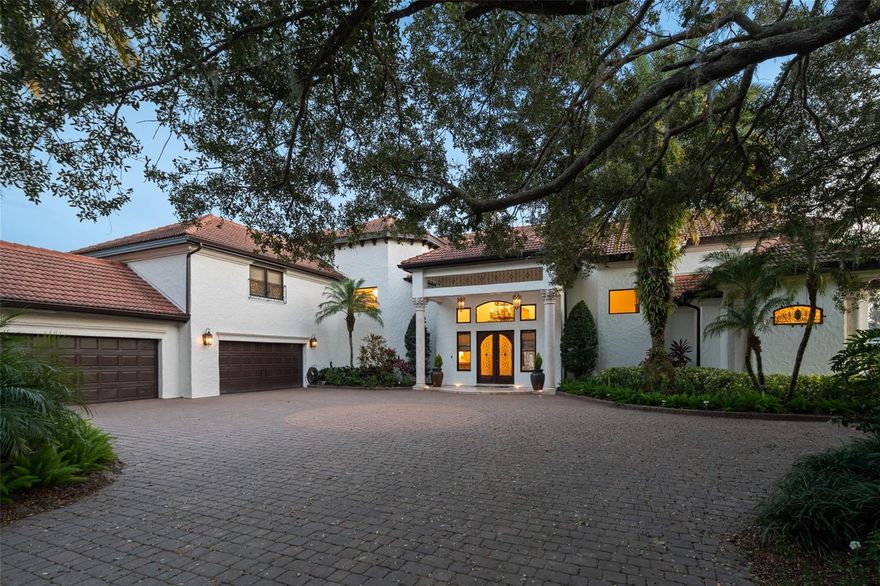 Offering a prime lakefront location along the shores of Lake Butler in the esteemed gated community of Chaine du Lac, this distinguished estate features timeless architecture paired with transitional interiors and gorgeous views to showcase Windermere lakefront living at its finest.  The estate has been elevated with significant recent improvements, including a brand-new roof, an all-new primary suite, a fully updated outdoor kitchen, and a $100,000 designer lighting package by Lightstyle of Orlando, all adding to the home’s sophistication and functionality.  Designed for effortless entertaining, the elegant living and dining rooms are highlighted by soaring ceilings and a dramatic double-sided fireplace, while the spacious family room and breakfast nook seamlessly connect to the kitchen and open to serene water views. The all-new primary suite has been fully reimagined with a new spa-like bathroom featuring elevated modern appointments including beautiful vanities, an oversized walk-in shower and a freestanding tub - elegantly accented by the home's new lighting package. The primary suite also features a gas fireplace and a private den, offering a quiet escape for a home office or study. A thoughtfully designed guest suite with its own sauna is also located on the main level, ensuring privacy and comfort for visitors. Upstairs, a media room and three ensuite bedrooms provide space and privacy, while a secondary staircase leads to a versatile game room with a full bar, half bath, and private balcony. A flexible cabana space presents options for a sixth bedroom, gym, or additional living area. The outdoors are equally captivating, with spacious sundeck surrounding a sparkling pool with fire pits. Additional highlights include the newly updated summer kitchen, a grand pergola featuring a loveseat swing and fireplace, a immaculate sand beachfront, and a double-slip boat dock. An expansive four-car garage, multiple energy-efficient air-conditioning systems, and a full-home generator complete the property. From golden sunsets to every carefully curated detail, the residence is framed by sweeping lakefront vistas and an ambiance of refined living.