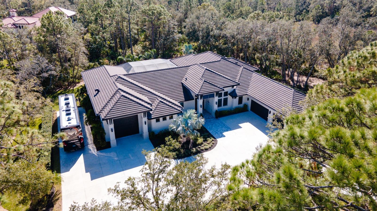 Welcome to this 2021 CUSTOM, SOLID-BUILT, 4 Bed + Study/Den, 4 Bath, COASTAL MODERN single-story home beautifully nestled on 3+ ACRE serene setting in the beautiful gated The Forest at The Hi Hat Ranches. The home features an oversized enclosed lanai with HEATED POOL and SPA and a well-equipped outdoor kitchen. There’s even an attached hidden DOGGIE RUN “relief” area along with a doggie door to the interior of the home. Additionally, this home has a 3-car garage plus an attached 20 x 60 FT. finished MOTORCOACH GARAGE complete with electricity (Three 50-Amp Outlets), A/C, full exhaust system, sink w/ hot and cold water as well as Washer/Dryer hook-ups. Car enthusiasts/collectors would benefit from this feature too as it has a 14 H x 12 W door. This EXTRA 1,244 SF of under air space could even be converted into a mother-in-law suite or nanny annex, w/permitting. As you pull into the circular driveway, you’ll love the warm, glowing accent lighting illuminating the home and the mature landscaping. Prepare to be impressed by the handsome porch and double glass doors as you approach the home. Upon entering the home you’ll be delighted by the 15ft. ceiling and huge window ahead looking over the pool and lanai area as well as the decorative open and illuminated art niches for your treasures. The entire home features 24 x 48 beautiful ITALIAN MARBLE tile with zero grout lines. Gourmet chefs and those who love to entertain will appreciate the huge Island, Quartz Countertops and custom cabinets along with a 6-Burner Wolf Stove, Sub-Zero Refrigerator and Double Wall Ovens. There’s also a clever hidden walk-in pantry with an Ice Machine and Wine Cooler. As an added striking design element, there’s a stunning floor-to-ceiling GLASS ENCLOSED WINE WALL where the bottles appear to float. The elegant Primary Bedroom has double doors, tray ceilings and an outside door to the pool/lanai area as well as an attached en-suite bathroom featuring a walk-through shower w/ electronic controls and sprayers, double sinks w/ infinity mirrors and a bidet. You’ll love the two walk-in closets w/built-in dressers. The 2nd and 3rd bedrooms also offer en-suite bathrooms. The “4th bedroom” is hidden by a built-in book/art shelf and could double as a SAFE ROOM! The formal dining room can accommodate a large table w/12 chair plus a built-in wall unit for your china and glassware. The whole house is WIFI enabled and has a Home Security System as well as being wired for Satellite TV. This is a RARE OPPORTUNITY for a discerning buyer!