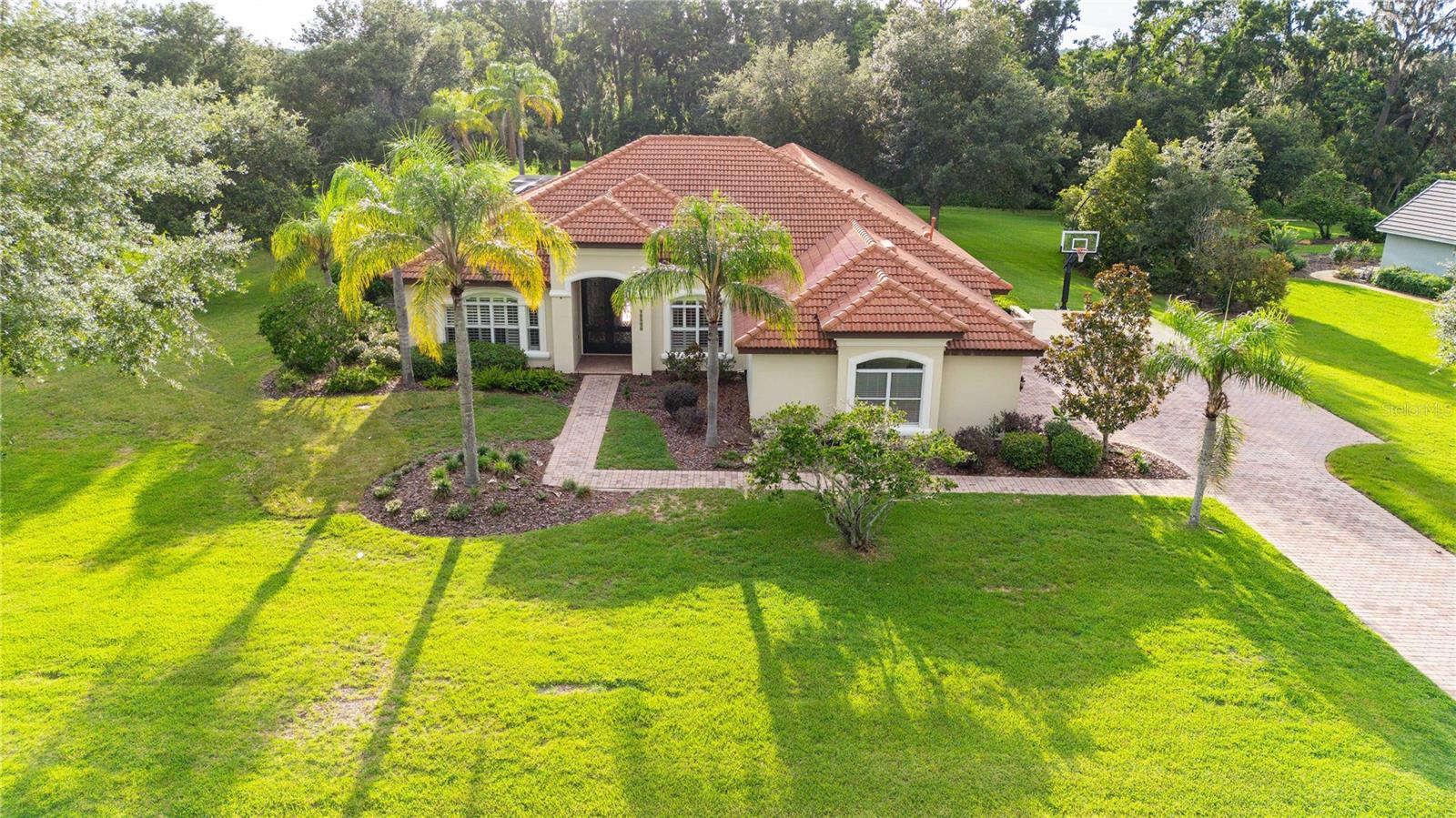 Tucked away on a spacious private lot in the guard gated community of Lake Jovita, this beautifully expanded home offers plenty of room to live, work, and play—with just the right blend of character, comfort, and flexibility. With six roomy bedrooms, a front office with closet and charming brick floors, and loads of adaptable spaces throughout, it’s designed to fit a variety of lifestyles, especially for families who appreciate warmth and privacy. In 2018, the home received a major refresh and addition, bringing in more bedrooms and baths, expanding the custom kitchen and family room, and adding a fabulous bonus space with a wet bar and dishwasher drawer—perfect for movie nights, entertaining, or simply kicking back. When you step through the welcoming double-door entry, and you’ll find a formal living and dining room with a striking tray ceiling, graceful crown molding, and wide-open views of the covered lanai, screen-enclosed pool and hot tub, and peaceful golf course beyond. The neighboring family room mirrors this elevated look with its own tray ceiling, cozy fireplace, and built-in surround sound, adding depth and ambiance to every moment. The heart of the home is the expanded kitchen, thoughtfully equipped with stainless steel KitchenAid appliances, double ovens, a walk-in pantry, soft-close drawers, a second pantry near the wet bar, and a butler’s pantry with cabinetry and a serving station. A large eat-at island anchors the space, while rich wood floors flow through the kitchen and family room, adding warmth and elegance. French doors from both the family room and breakfast nook open to the screened outdoor area, creating a seamless transition for indoor-outdoor living all year round. Two primary suites offer comfort and flexibility and the split plan layout could be perfect for joining or multi-generational families. The main retreat features a remodeled bath with jetted tub, dual walk-in closets, a private workout or flex space, and views of the pool, while the second suite is perfect for guests, teens, or extended family. Other highlights include a study nook with built-in lighting, two fireplaces, plantation shutters throughout, and two laundry rooms, including a primary laundry area off the garage with enough space to function as a convenient mud room. The home also features surround sound throughout with amplifier and control 4 system, enhancing daily life whether you're watching a film, listening to music, or setting the mood for a quiet night in. Continue the activities outside with your basketball goal and spotlight conveniently located in your driveway. The home also includes a home water softener and a WHOLE HOME GENERATOR for your peace of mind and uninterrupted power during unpredictable weather. End your days stepping outside on your lanai to experience the breathtaking sunset views down the 14th fairway of the North Course of Lake Jovita. Take advantage of all Lake Jovita has to offer inclusive of a park with a one-third mile long track with exercise stations, pickleball courts, basketball courts, a playground area, a large open area for any use requiring a field, and two dog parks. The optional clubhouse memberships are also available to enjoy all the additional features of the community including any Club facility, such as the golf course, clubhouse, swimming pool, tennis courts or golf practice facilities. So much to offer in one home you must see it for yourself!