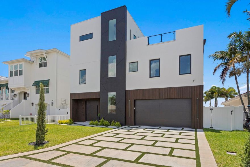 Modern Masterpiece in North Redington Beach by Spinelli Real Estate Development. This modern three-story coastal location one and a half blocks from the beach features a spectacular turf rooftop terrace offering over 1,200 SF of stunning beach vistas and captivating sunsets. Every custom detail has been addressed from a dramatic 20ft cascading chandelier and expansive iron pivot front entry door, climate-controlled wine cellar, and 9 car garage. Floor to ceiling windows and soaring ceilings provide the backdrop for impressive entertaining in an open floor plan. The second floor delivers an outstanding chef’s kitchen with quartz waterfall island, top-of-the-line appliances (Thermador) and butler’s pantry overlooking the dining area and family room. The second level also features an ensuite guest bedroom, powder bath and 2 more bedrooms, an Outdoor Kitchen and expansive marble lanai. A 3-stop elevator assures easy transition from floor to floor, with the third level offering a grand master retreat. The private primary oasis provides large sliders to a terrace overlooking the intercoastal, indulgent spa-inspired bath and custom closet/dressing area. The third level boasts an expansive walk around rooftop terrace along with an entertaining bar and putting green. The ground level is all about entertaining with a spacious covered lanai, fully automated salt water pool, 360 infinity spa and marble/turf expansive deck. Additional features include luxury vinyl flooring throughout, Custom built Closets, custom Italian cabinetry, gas appliances and tankless water heater, dual laundry room, outdoor surround sound, smart home pre wire, camera system and tropical landscape. Deep water canal with 2017 seawall and dock. In desirable North Redington Beach Dolphin Dr canal, you are just moments from the pristine Gulf beach and the vibrant energy of coastal living. Minutes to local festivals, restaurants, golf and entertainment! This is a perfect beach paradise to live like you’re on vacation every day. Enjoy the many nearby dining options, John's Pass, Clearwater Beach and downtown St. Pete, with easy access to Tampa International Airport.