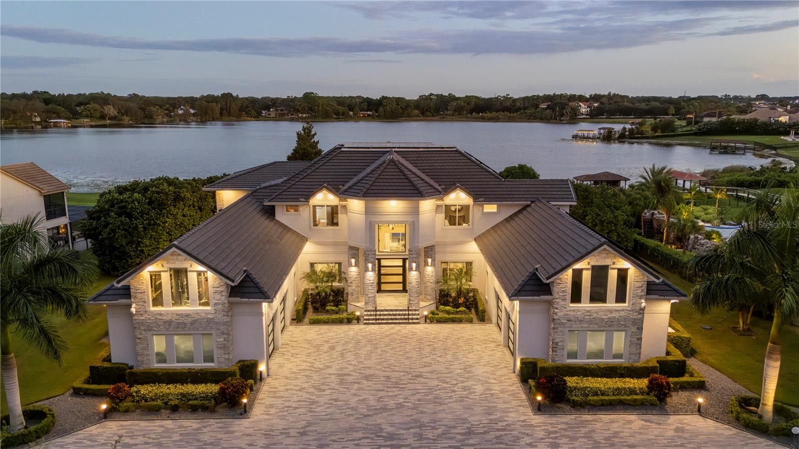 Discover this exceptional estate, recently renovated in 2021/2022, offering over 8,000 square feet of unparalleled craftsmanship. Upon entering, you are welcomed by a bright, open floor plan featuring a magnificent two-story foyer and a grand staircase adorned with custom glass railings, all framed by breathtaking lake views from every window and door. The gourmet kitchen showcases exquisite European-inspired custom cabinetry, top-of-the-line Gaggenau appliances, and a generous kitchen island, perfect for both culinary enthusiasts and entertaining. The master wing is a true retreat, boasting a luxurious spa bath, a separate lounge area, and a unique custom closet. This magnificent residence includes six bedrooms, seven full baths, and two half baths, along with a game room, gym, sauna, and a state-of-the-art home theater. Advanced technology throughout the home is powered by Lutron, ensuring convenience and sophistication at every turn. The outdoor space is equally impressive, featuring an infinity-edge pool enveloped in glimmering imported glass tile, set against a stunning 1.3-acre lot on Lake Davis. The private dock includes a second-story sun deck, providing an ideal spot for relaxation and enjoyment. The home is equipped with a new roof in 2023 and Tesla solar panels and a backup generator, ensuring energy efficiency and reliability. Water is purified by a reverse osmosis system, and each bath is custom finished, featuring Toto automatic and heated toilets. The landscaped backyard boasts several fruit and citrus trees, including mango, avocado, lemon, peach, lime, star fruit, and guava. Located just minutes from world-class shopping, fine dining, downtown Windermere, and the area’s renowned theme parks, Tildens Grove offers a prestigious lifestyle in a secure environment. Don’t miss this extraordinary opportunity to own a truly remarkable residence.