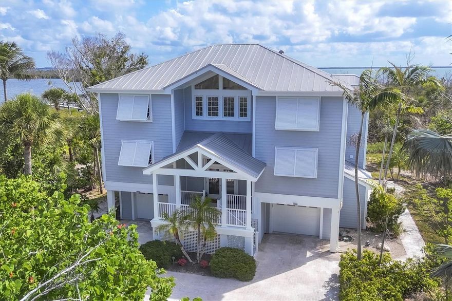 Located on Gasparilla Island beyond a private driveway, this one-of-a-kind retreat spans generous acreage and captures panoramic bay and coastal water views. Positioned on 1.88 acres and framed by native landscaping, the serene setting feels worlds away, yet remains just minutes from the charm of Boca Grande village.
Spanning 2,951 square feet of refined living space with a total footprint of 6,287 square feet, the residence features three bedrooms plus a study or bonus room that can easily serve as a fourth bedroom, along with three-and-a-half baths. An interior elevator services all floors, ensuring effortless access throughout. The interiors reflect a sophisticated coastal aesthetic, highlighted by light-colored hardwood floors and thoughtfully designed living spaces.
The study features a wet bar, opens to an exterior porch, and offers a perfect spot for stargazing, while the upstairs primary suite enjoys its own private porch—both providing sweeping Bay views and front-row seats to abundant wildlife, including osprey, pelicans, and egrets. An expansive porch running the length of the home invites morning coffee with sunrises over the water and evenings bathed in soft sunset hues. Electric hurricane shutters provide peace of mind, while the three-car, climate-controlled garage plus dedicated golf cart space adds everyday convenience.
Leisurely bike rides or golf cart trips along the paved path lead directly into the village of Boca Grande, known for exceptional dining, unique shopping, world-class fishing, and outstanding boating. Properties of this size, setting, and water-view presence are exceptionally rare on the island, making this a truly special opportunity.