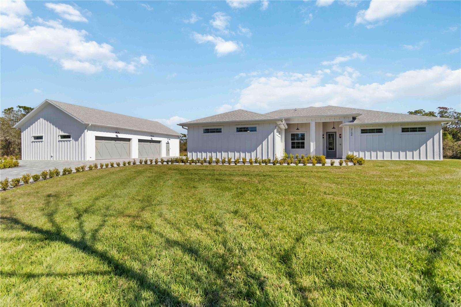 OWNER FINANCING AVAILABLE. This one of a kind custom luxury modern farmhouse was meticulously designed for the most discerning tastes & over engineered to withstand severe hurricane-force winds, mitigate flood risk, and be energy efficient. Nestled on over 1.1acres of pristine land, it epitomizes the essence of high-end ‘country’ living with the convenience of being less than 5 minutes from I75. This exclusive highly elevated property features a custom designed 5,000 SqFt paver walkway, driveway, and RV parking area, with 300 shrubs outlining its perimeter leading you to the main house with attached oversized 2-car garage and separate guest house with attached oversized 4 car garage. Both structures were designed and constructed to compliment each other with custom vertical board-and-batten on all exterior walls, solid non-vented soffits, custom half round 6” gutters, 4 insulated wood paneled garage doors, designer marine grade lights over all garage doors, guest house private entry, main house front entry, hand stained cypress tongue & groove wood installed on exterior ceilings, massive pool with a 7’ x 35’ sunshelf, and custom high-end commercial grade whole house RO system. The interior of the main house and guest house is a masterpiece of old-world craftsmanship. Meticulously designed with the finest hand picked finishes: Cristallo, Taj Mahal, and other quartzite countertops in all 3 bathrooms, matching full height quartzite backsplashes in 2 full size kitchens and laundry room | European white oak wire brushed wood floors in the main house | Imported marble on all bathroom floors, walls, shower ceilings, and guest house living area, and pool deck | Custom 8’ solid core interior wood doors | Custom designed bathroom cabinets | Custom built floor-to-ceiling cabinetry the two full size kitchens and laundry room | Custom kitchen island with hand stained oak cabinets & 6 cm mitered countertop | Custom hand stained and vented radius range hood | Designer knurled cabinet hardware | Custom vertical tongue & groove cypress on all common area walls and bedroom accent walls | Custom double stacked crown molding | Custom full extension window casings (including garages) | Custom door casings | Custom baseboards (including garages) | Designer Moen Weymouth and Hansgrohe plumbing fixtures | Designer lighting fixtures and walnut fans | Light dimmers on all lights | Custom closet systems | All interior walls are insulated | Open cell insulation | Custom designed HVAC systems with standalone built in whole house dehumidifiers and fresh air systems | Industrial grade epoxy floors on all garage flooring. Other notable features include: All exterior walls are solid poured reinforced concrete walls and contain R-25 insulation on the exterior and interior envelope walls | All windows and doors are impact-resistant insulated low-e | 25 yr shingle roof with peel and stick underlayment | Built on a 64 inch tall solid poured and waterproofed stem wall | 300 additional (18 yard dump truck) loads of fill dirt and crushed concrete ensure the entire area around both structures exceeded all elevation requirements | Eligible for FEMA’s optional LOMR-F. Simply put, this combination of thoughtful design & over engineering offers peace of mind, thus ensuring tranquility in equal measure. Experience the pinnacle of luxury living and enduring quality craftsmanship with its panoramic views, lush surroundings, and timeless elegance. Your dream retreat awaits!