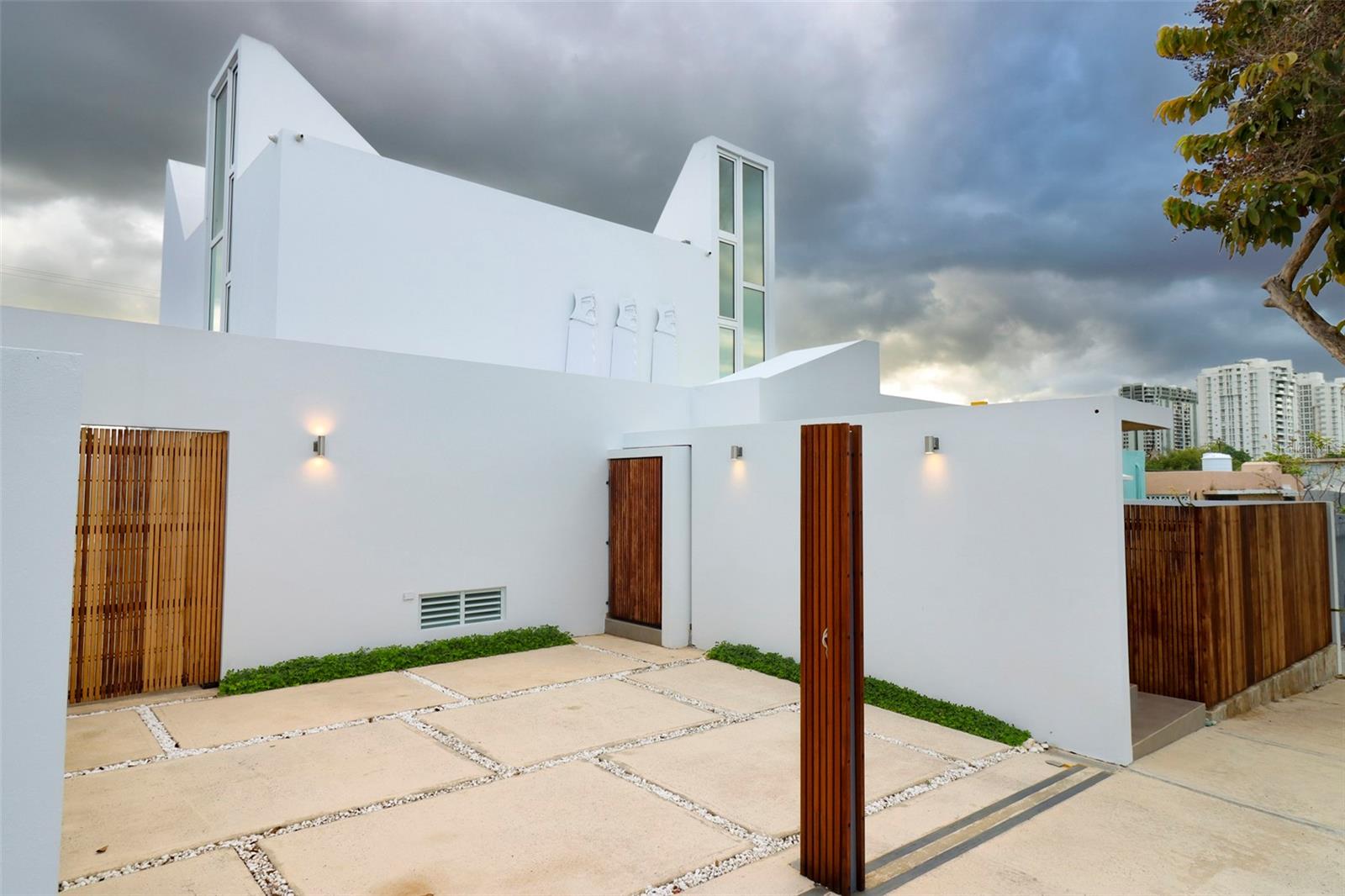 AVAILABLE! Casa Zen – A Livable Work of Art
Casa Zen is an architectural masterpiece built and designed by renowned, award-winning architect Nathaniel Fuster, recognized by the American Institute of Architects and at the Biennial of Architecture of Puerto Rico.
More than a residence, Casa Zen is a livable work of art that blends a unique sensorial and spiritual experience. The structure is built seismically on a concrete slab and features a grounding node integrated throughout its steel and concrete framework, which forms the entire body of the property. The house rises in two energetic modules that foster Zen experiences of meditation and creative development. The first consists of four 17-foot-high centrifugal concrete cones that open toward the sky, offering a constant interplay of clouds, moonlight, stars, sunlight, and rain—creating shifting light, shadows, and tones within the home. The second module features four centripetal concrete cones designed to capture air currents, channel energy inward, and generate a sensorial atmosphere where private living merges with nature.
The property includes fourteen gardens located throughout rooms and shared spaces, blending with a pond and a sky-open swimming pool. This promotes a private, secure, and intimate lifestyle in continuous contact with light, ventilation, and water, cultivating a Zen-like climate and energy. These environments can be personalized according to the spiritual preferences of the future owner, granting the home an energetic and personal signature. More than aesthetic customization, the residence reflects energies of development and progress aligned with its future occupant.
Casa Zen features robust smart home infrastructure, with approximately forty smart devices, high-speed fiber-optic internet capable of reaching up to 4,000 megabits persecond, and advanced security systems.
Strategically located in the urban core of San Juan, in the island’s oldest residential development, the property sits just 5 minutes from Puerto Rico’s Financial District, key hospitals, and the Plaza Las Américas shopping center—and only 15 minutes from cultural institutions and Condado, the city’s main tourist hub. Casa Zen offers unmatched access and mobility throughout San Juan and its metropolitan area. It is ideal both as a private residence and as a creative venue for filming, art, or exclusive events. Companies such as Sony Pictures and major fashion brands have already expressed interest.
Additionally, Puerto Rico offers fiscal incentives under Act 60, such as reduced corporate tax rates of 4percent, dividend exemptions, and benefits for international investors. Casa Zen is not only a sensory sanctuary—it is a Strategic Investment that merges Life and Time.