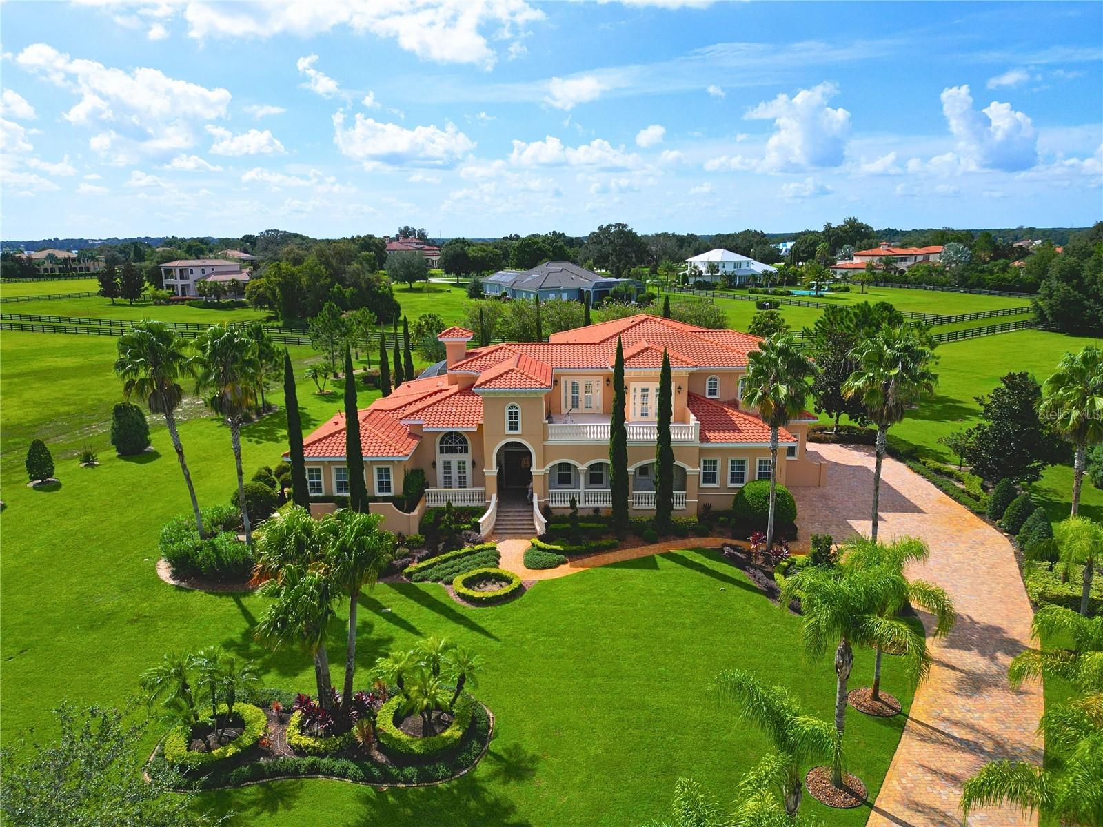 This luxurious 5 bedroom, 6 bathroom estate spans an impressive 6,606 square feet on almost 2 acres in this private gated and guarded community. Throughout you'll find upgraded options like crown molding, tray ceilings, elegant light fixtures, as well as a wood built-in entertainers bar. The GOURMET KITCHEN, complete with top-of-the-line stainless steel appliances with brands like Thermador, custom cabinetry, granite countertops, and a double two-toned island, is an entertainers dream. Complete with a formal dining room enclosed in stone columns, a spacious foyer, and a grand living room with 20'+ ceilings and gas fireplace. Conveniently located you'll find the Primary bedroom as well as 1 additional on-suite bedroom on the first level which is great for MULTI-GENERATIONAL Living, with remaining 3 bedrooms upstairs. The master suite, a private sanctuary with his/her closets has a spa-like en-suite bathroom with a garden tub, spacious walk-in shower, and dual sink vanities, offering a perfect escape at the end of the day. Upstairs you will find a secondary kitchen, bonus/game room as well as three additional bedrooms, each generously sized and featuring their own en-suite bathroom and walk out balcony. Outside, you can indulge in the vast lanai space with 5 separate seating areas, a built-in stone OUTDOOR KITCHEN, and a large BEACH-ENTRY POOL and spa. Beyond the home's comforts, Stonelake Ranch offers a wealth of amenities, including a serene community lake lodge sitting on Lake Thonotosassa with a boat ramp, tennis courts, basketball court, and park which is perfect for embracing the ultimate lifestyle.