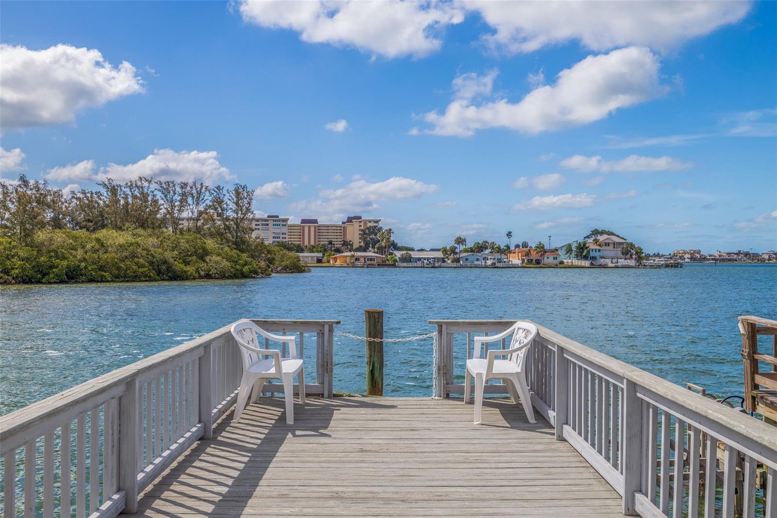 Some refer to this 24-hour guard gated 55+ Waterfront Boating Community at Boca Ciega Point as Paradise, and I could not agree more! The community features tennis courts, pickleball, putting green, bocce, shuffleboard, a large pool that is heated in the winter and cooled in the summer, a sauna, library, card room, a new workout facility, and a clubhouse which features a pool table, darts, a shuffleboard table, and a large kitchen for entertaining. On the social side, join the Boat Club and/or participate in the various activities included on the monthly Social Calendar. There are 2.5 miles for those who enjoy morning or evening walks, with or without their dog. Watch gorgeous sunsets from your dock or go 2 miles to Madeira Beach!
Now for the best part, as you enter this 1400 sq ft Fully Furnished Waterfront Villa, your immediate attention is drawn to the pristine water view of the Intracoastal, where dolphins and manatees swim around almost daily. The Villa has a wide-open floor plan with porcelain tile flooring throughout the villa. The two large bedrooms include large closets. Hurricane Accordion Sliders, a dock with plenty of room to add a boat lift, new AC (2020), a new Water Heater (2022), a new roof (2021), a water softener, and an oversized one-car garage with an exterior parking pad on the driveway. The Association fee includes a 24-hour guard gate, private road, cable, internet, trash, water, sewer, building insurance, flood insurance, common area taxes, community pool, lawn service, most maintenance repairs, manager, and recreational facilities.
