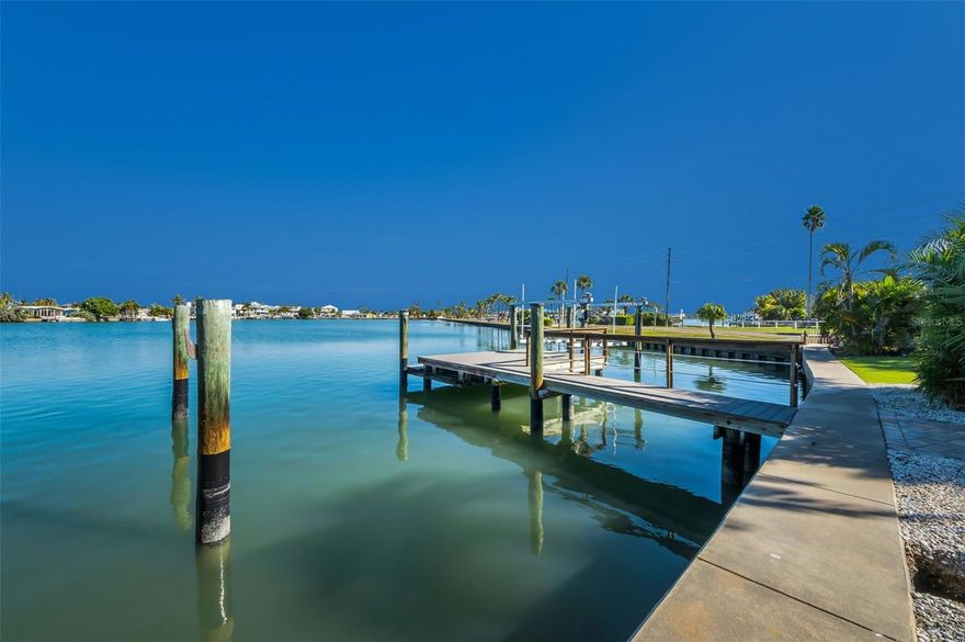 Discover the ultimate blend of serenity and coastal convenience with 82 feet on some of the best, deep-water frontage in Redington Beach on a protected lagoon yet seconds to the intracoastal waterways of Boca Ciega Bay.
Spanning 2,056 sq ft, this light-filled 4-bedroom, 2.5-bathroom home offers soaring 9.5-ft ceilings, an expansive open-concept layout, and breathtaking water views from the kitchen, living, and dining areas. A generous waterfront bonus room—currently ideal as a sunroom or home office—presents the flexibility to become a 5th bedroom. Hurricane-impact windows throughout PLUS roll down hurricane shutters on the immense picture windows for double protection provide strength against storms and bathe the interiors in natural light.
The spacious primary bedroom with ensuite is situated down the hallway ensuring peace and quiet.  The second and third bedrooms allow ample space for family and friends.  
A custom designed wood six bunk bed system has been carefully preserved and is ready to be set up in the third bedroom.  The expansive fourth bedroom has a wood burning fireplace for rest and relaxation.  Neutral terrazzo floors throughout offer timeless, durable, coastal beauty.
Step outside to your resort-style backyard: a spacious brick-paver patio framed by low-maintenance artificial turf and lush, mature landscaping creates a hard-to-find intimate outdoor living area. A hidden west-side sanctuary offers endless possibilities—a secret garden, zen retreat, shaded play area, or your own private oasis.  A composite dock features two slips, one with a boat lift, allowing you to be cruising the intracoastal waterways, the other with deep sail boat water.
A leisurely 3-block stroll brings you to the sugar-sand shores and sparkling waters of the Gulf, with exclusive resident-only parking at Redington Beach.  Other notable features: expansive brick paver drive, brand-new roof in 2025, 2013 seawall, flood gates, and whole home custom mahogany trim that has been salvaged and cleaned.  Redington Beach ALLOWS short term rentals.  Home deemed NOT Substantially Damaged.
