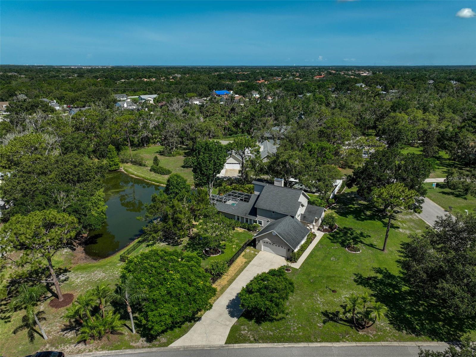 Welcome to this absolutely stunning Mill Creek retreat, perfectly positioned on a spacious 1-acre corner lot with serene pond views. This beautifully updated two-story pool home includes two new AC units with a 10-year fully transferrable warranty (2025) two newer water heaters (2019) newer roof (2017) new gutters, shutters, irrigation, reverse osmosis system and fenced yard. Relax in this peaceful setting that is truly a sanctuary with a screened lanai overlooking your private pool or unwind beneath the oversized retractable awning. The fully fenced yard offers peace and privacy with no rear neighbors, a side-entry garage and plenty of parking – including room for an RV, boat or potential outbuilding! Inside, no detail has been overlooked – from gleaming hardwood floors and a custom wood-burning fireplace to marble countertops, stainless steel appliances, wine fridge and soft-close cabinetry. The open-concept design features soaring ceilings and thoughtful finishes throughout. Upstairs, the private primary suite includes dual walk-in closets and a luxurious ensuite bath with a massive walk-in shower and dual vanities. Enjoy full automation capabilities with the app controlled front door, garage door, washer, dryer, thermostat and ring doorbell. The alarm system monitors all windows and doors and includes motion detector sensors, 4 exterior cameras and an interior camera. The refrigerator door has a Krupps coffee maker attachment and the primary bath showerhead has a Bluetooth speaker. Bonus features include a charming storage shed that could be converted into a workshop and a putting green to practice your golf game! Located in the highly sought-after community of Mill Creek that offers large lot properties and architectural diversity so lacking in today’s new communities, with easy access to I-75, top-rated beaches, airports, dining and more – this one truly has it all!