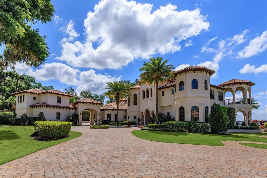 Presenting Sunset Isle: an iconic waterfront estate compound capturing timeless elegance on Windermere’s largest and most prestigious Lake Butler, offering captivating unobstructed views from its 700 feet of lake frontage, a private island with moat and drawbridge, sandy beaches, two story double residence guest house, and a majestic and stunning grand mansion with additional guest retreat, all spanning more than 14,444 square feet of living space and 11 bedrooms across both residences. Welcome to this one-of-a-kind haven of privacy and prominence showcasing the best of Central Florida living. Set on a rare 3.75 acres commanding enviable views on the northern shore of Lake Butler, every detail has been thoughtfully designed to celebrate both refinement and tranquility. The impressive palatial main residence boasts 10,649 square feet of living space with 6 bedrooms plus a one-bedroom guest retreat and an array of curated spaces. The Spanish Eclectic interior fuses classic craftsmanship with modern sophistication, creating an inviting and awe-inspiring escape from the ordinary. On entrance be greeted by sweeping floor to ceiling windows to allow breathtaking water vistas, double-sided gas fireplace, a grand colonnade hallway, and architectural details throughout. The gourmet chef’s kitchen features top of the line appliances, gas range with multiple burners, ovens, island with second sink, and walk-in pantry. A sports bar games room and showstopping home theater provide an abundance of entertaining options. Other notable amenities include a Castilian wine cellar, bay windows, two wet bars, private salon, elevator, gym, steam room and sauna. Outdoors, a generous summer kitchen with automatic roller screens provide an outdoor oasis for al fresco dining, cooking, or relaxing. The zero-entry infinity pool and vast resort decking provide a breathtaking vantage point for panoramic views of Lake Butler’s radiant sunsets, while the shaded Zen garden and white sandy beach offer a tranquil retreat for quiet reflection. With many distinct outdoor venues, serenity is never far away. The estate’s private island, accessed by an electric drawbridge, and a boat ramp provide unmatched exclusivity to Lake Butler and the world-famous Butler Chain of Lakes. The two-story detached guest house offers 3,795 sq feet of living space across two, 2-bedroom apartment homes, each with kitchens, laundry rooms, an elevator, and attached two-car garage. Built for a large multi-generational family, guest quarters, or on-site caretakers, the possibilities are endless. Truly a picture-perfect unmistakable showplace offering the very best for the most discriminating buyer. ** HOME SALE COMES WITH A 2-YEAR LEASE ON A 2025 ROLLS-ROYCE DAWN, WITH ACCEPTABLE OFFER.  ASK FOR DETAILS. **