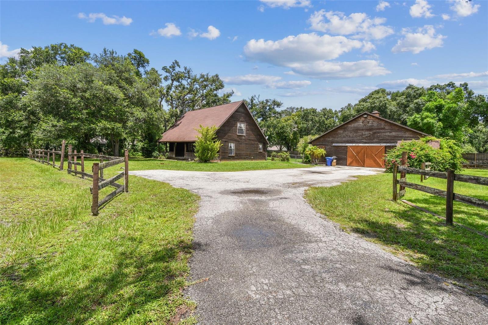 Wide Open Spaces await you in the Sought-After Community of Sundance! Nestled on 1.74 acres, this charming cedar plank home is ideal for equestrian enthusiasts or anyone looking for extra space to breathe, work, or create. With a massive barn—currently featuring two horse stalls—you have the perfect blank canvas to design your dream workshop, studio, or additional stabling. Inside, the home offers just under 1,800 square feet of inviting living space, complete with solid wood flooring throughout. The main-floor owner's suite features dual walk-in closets, while two additional bedrooms upstairs share a full bathroom, offering privacy and comfort for family or guests. The efficient galley-style kitchen maximizes space and function, making meal prep a breeze. Step onto the expansive front porch to enjoy your morning coffee and take in the peaceful sounds of nature. Sundance offers the tranquility of rural Florida living with the convenience of being just off US-301, putting shopping, dining, and everyday necessities only minutes away. Call today to schedule your private showing and discover the unique charm and possibilities this property has to offer!