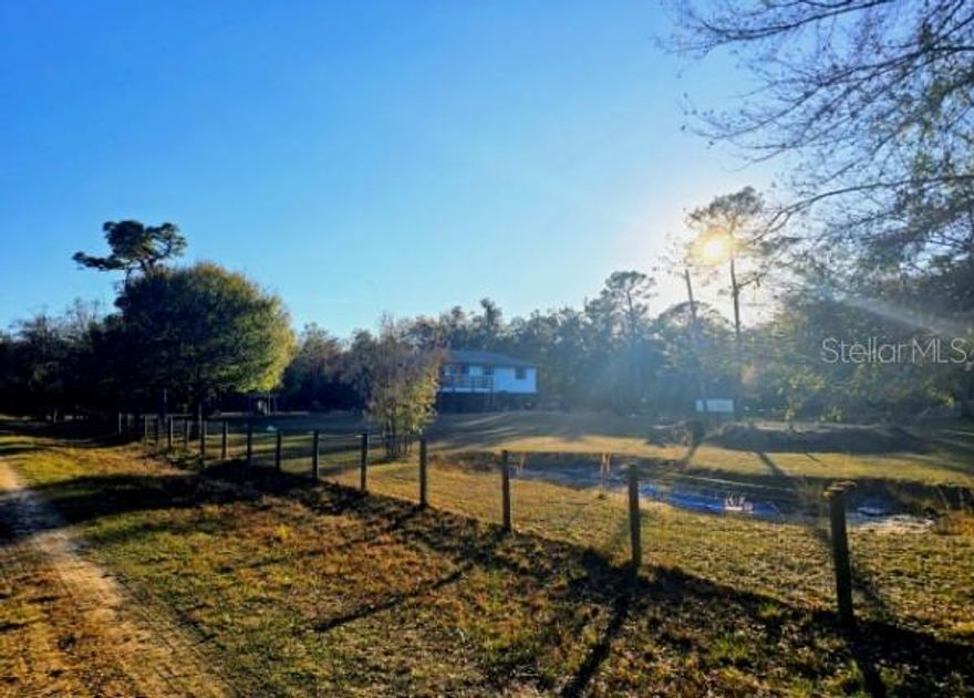 Situated on 2.67 fully fenced acres, this Arcadia horse property for sale offers a rare opportunity to own usable agricultural land with established improvements in a peaceful rural setting. Zoned A-5, the property allows horses, livestock, and agricultural use, making it well-suited for equestrian buyers, hobby farmers, or those seeking acreage with flexibility and privacy.

The elevated residence features 2 bedrooms and 1 bath, thoughtfully positioned to overlook the land and surrounding greenery. While modest in size, the home provides comfortable living space with an open layout and wraparound outdoor areas ideal for enjoying the property year-round. A covered under-home area provides parking, storage, and workspace options.

The land itself is the standout feature. Improvements include a barn, multiple outbuildings, a horse stall, feed and storage areas, and multiple ponds that support livestock and enhance the natural setting. The acreage is fully enclosed and ready for animals, with established fencing already in place. Mature trees, open pasture, and functional farm infrastructure create a property that can be used immediately without major upfront investment.

Located just outside downtown Arcadia, this horse property with acreage offers the balance of rural privacy and convenient access to town amenities, highways, and surrounding Southwest Florida markets. Properties offering AG zoning, usable fenced land, and existing farm structures are increasingly difficult to find, particularly at this size and location.

Whether you’re looking for a horse farm, a hobby farm, or a rural Florida property where the land provides real value, this offering presents a practical, versatile opportunity in one of DeSoto County’s most sought-after agricultural areas.