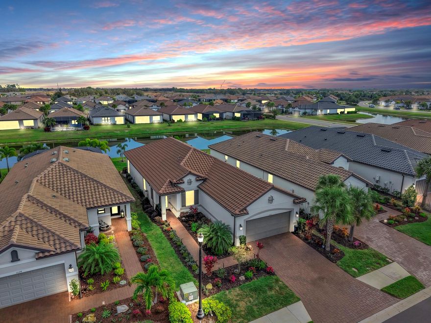 PRICE IMPROVEMENT! Enjoy resort style & maintenance free living in this beautifully updated Matera model, offering 3 bedrooms, 2.5 bathrooms, an open floor plan, and tranquil water views that set the tone for relaxed Florida living. From the moment you arrive, attention to detail is evident with upgraded landscaping and lighting, rain gutters, and a sealed paver driveway. A whole-home water softener and purification system adds comfort and convenience throughout the home. Inside, the space feels open, bright, and inviting. The kitchen, dining, and living areas flow seamlessly together, making this home ideal for everyday living and entertaining. Wood-look porcelain tile runs throughout the main living areas, creating a clean, cohesive aesthetic that is both stylish and easy to maintain. Crown molding, updated lighting, and ceiling fans provide a refined finish, while tray ceilings and 8' doors enhance the home’s open, airy feel. Plantation shutters add timeless character, complemented by sun screens that provide privacy and help manage the Florida sun. The kitchen is thoughtfully designed with a herringbone tile backsplash, a functional island, a dedicated nook ideal for a coffee or beverage station, and a five-stage water filtration system at the sink. Custom pantry shelving enhances storage and organization. Nearby, the laundry room features additional cabinetry and a window that brings in natural light. The home offers a desirable split-bedroom layout, with the primary suite privately situated at the rear to take full advantage of peaceful water views. Two additional bedrooms are located at the front of the home, providing excellent separation for guests, family, or a home office. The primary suite serves as a relaxing retreat and features an ensuite bathroom with double vanities, a spacious walk-in shower with an upgraded rain shower head and frameless glass enclosure, and a custom walk-in closet with built-in storage. Step outside to the extended lanai overlooking the water, where it’s easy to imagine enjoying this space year-round. The lanai is plumbed for an outdoor kitchen, includes a sink and ceiling fan, and offers ample room to add a pool. Remote-controlled sun shades allow you to comfortably enjoy the view—whether you’re having morning coffee, entertaining, or unwinding at the end of the day. The extended garage with a 4-foot extension adds exceptional value, featuring an epoxy-coated floor, custom cabinetry, overhead storage, an organizer system, and a dedicated breaker ready for a home generator. Esplanade at Artisan Lakes offers unmatched resort-style amenities, including two clubhouse centers with beautifully designed social and activity spaces. Residents enjoy two resort-style pools, a resistance pool, two spas, a state-of-the-art fitness center, movement studio, and outdoor recreation such as tennis, pickleball, bocce ball, and cornhole. Additional highlights include a fire pit, multiple lounging areas, both small and large dog parks, and a playground. A full-time lifestyle manager curates events, clubs, and activities, creating a vibrant community atmosphere. Conveniently located near I-75 and I-275, this home provides easy access to Tampa, St. Petersburg, Bradenton, Sarasota, airports, dining, shopping, golf, and the sparkling Gulf Coast beaches. *See attached video and 3D Tour*