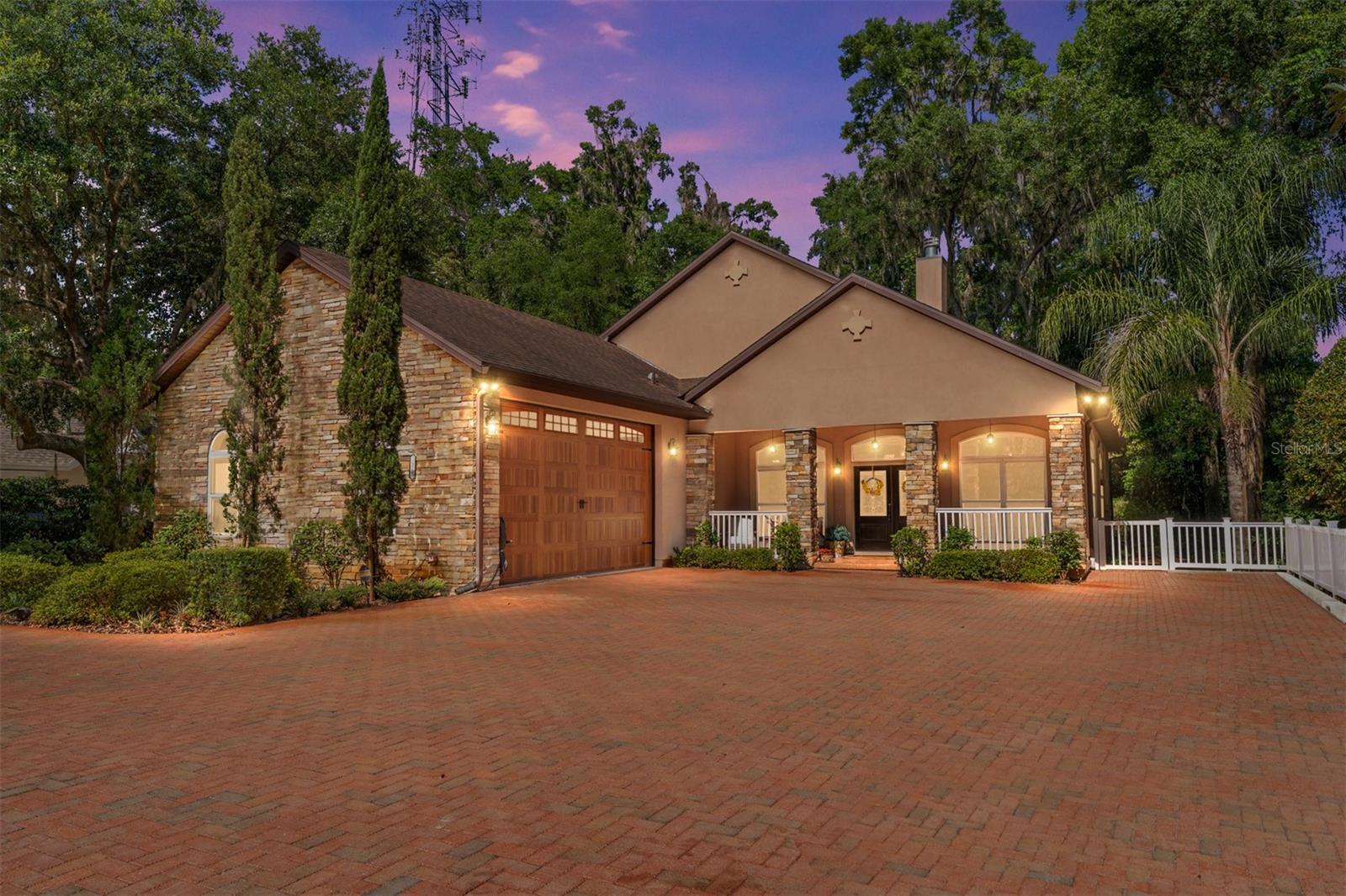 Nestled among mature trees in one of Jonesville’s most sought-after communities, this stunning custom-built residence offers refined living in a serene, nature-inspired setting—just moments from the conveniences of Gainesville, Newberry, and I-75. Built in 2017 by a prominent local developer, this thoughtfully designed 3-bedroom, 3-bath home with a dedicated office and a versatile 3-way split plan offers exceptional craftsmanship, curated finishes, and a lifestyle of comfort and ease. From the moment you arrive, the curb appeal impresses with an expansive brick-paver driveway, welcoming guests to an inviting front porch with double seating areas—perfect for morning coffee or evening conversations. Inside, a light-filled open concept layout is framed by soaring double-insulated windows and transoms in every room, capturing peaceful views of the surrounding trees and offering a daily show of birdlife and changing seasons. The front living and dining room exudes warmth with a stone-accented fireplace, ideal for elegant entertaining or cozy nights in. At the heart of the home lies an extraordinary chef’s kitchen, designed for both grand gatherings and intimate meals. Anchored by a massive central island and two bar areas, the kitchen features custom real-wood cabinetry, premium granite countertops, built-in wall oven and microwave, cooktop, large dual sinks—one perfectly positioned under a window—and thoughtful additions like two wine refrigerators and a dedicated ice maker. Nearby, an enormous walk-in pantry and spacious laundry room offer functionality that matches the home's style. The owner's suite is a true retreat—expansive and serene—with a private fireplace, luxurious en-suite bath featuring upgraded granite, real wood cabinetry, a soaking tub, a separate walk-in shower, linen closet, and dual walk-in closets. Two additional oversized bedrooms share a beautifully appointed bathroom that opens directly to a screened-in lanai, where nature and comfort converge. This impressive outdoor living space features a full summer kitchen with built-in grill, refrigerator, custom cabinetry, a hot tub, and abundant space for dining and lounging—all framed by forest views that create a feeling of total privacy. Back inside, a large family room provides a third fireplace and even more space for relaxing or entertaining. The dedicated office offers a quiet escape for working from home or managing your household. With tile and hardwood flooring throughout (no carpet in sight), triple fireplaces, designer finishes, and a floor plan that blends openness with separation, this home is designed for those who value quality and tranquility. And when it's time to entertain on a grander scale, you're just a short walk to the Arbor Greens community pool and clubhouse—complete with a full kitchen and gathering space for events and celebrations. Don’t miss this rare opportunity to own a private, nature-rich retreat in a prestigious neighborhood that offers both seclusion and connectivity. Schedule your private showing today and experience the lifestyle you've been waiting for.