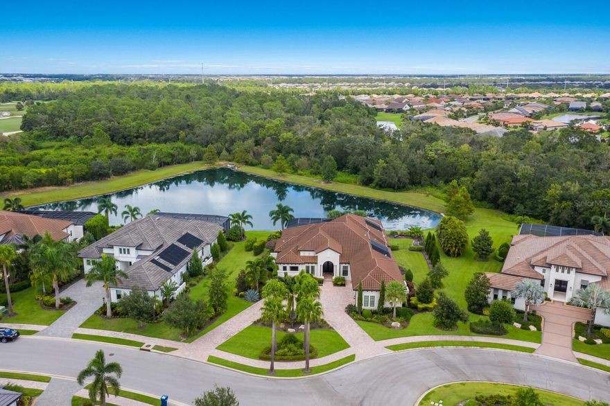 Situated on almost a half acre with stellar lake and preserve views, this meticulously designed and expanded Talia residence in the sought-after Eaglescliffe enclave in Country Club East showcases generously proportioned indoor-outdoor spaces, exceptional craftsmanship, refined architectural details, AND even boasts an oversized garage with car lift.  Built by John Cannon Homes in 2018 offering 3,434 square feet of expansive one-story open living on a premier Lakewood Ranch lot with circular front drive, and an expanded lanai with a panoramic clear view screen, abundant open and under cover spaces, full summer kitchen, gas firepit, PebbleTec heated saltwater pool and large spa. 

Seamlessly connecting this resort-styled lanai to the oversized great room and dining area are disappearing 10’ impact glass doors that reveal a large open living concept with voluminous tray ceilings and wood beam detailing. Meanwhile chefs will delight in the beautifully appointed gourmand’s kitchen with SubZero, Wolf and Bosch appliances, sprawling stone counters, custom cabinetry with dovetail soft-close drawers, pull-out storage upgrades, reverse osmosis and a hidden walk-in pantry. 

Behind double French doors off the great room, lanai, and full pool bath is a voluminous bonus room with disappearing impact glass walls that open to reveal the serene outdoors. Additionally the residence offers an office with double-entry doors, built-in shelving and bench, shutters and wood flooring.  

Relax and unwind in the elegant owner’s retreat positioned on its own private wing, offering two oversized walk-in customized closets, and a luxuriously appointed spa-like bath with dual sink vanity, and both indoor and outdoor showers. Overnight visitors will be right at home in two generous guest suites both with ensuite full baths. 

Other highlights of this 5,063 total square foot three bedroom and four full bath residence includes all impact windows and doors, a wine bar with two temperature-controlled refrigerators, built-in mud room storage and cabinetry, laundry room with cabinetry, sink, and closet, fenced back yard, tankless water heater, whole-house water softener, and rarely-available four car garage option with the addition of a car lift in this oversized 3-car garage with air-conditioned wall unit.

Country Club East provides its residents with the privacy of gated-community living, three community pools, fitness center and easy accessibility to world-class shopping, dining, medical facilities & I-75, for an unparalleled lifestyle defined by relaxation & recreation. Residents also have the non-mandatory option to become members of the Lakewood Ranch Golf and Country Club, which offers three championship golf courses, two clubhouses, tennis, pickelball, fitness center, heated pools, full social calendar and so much more.