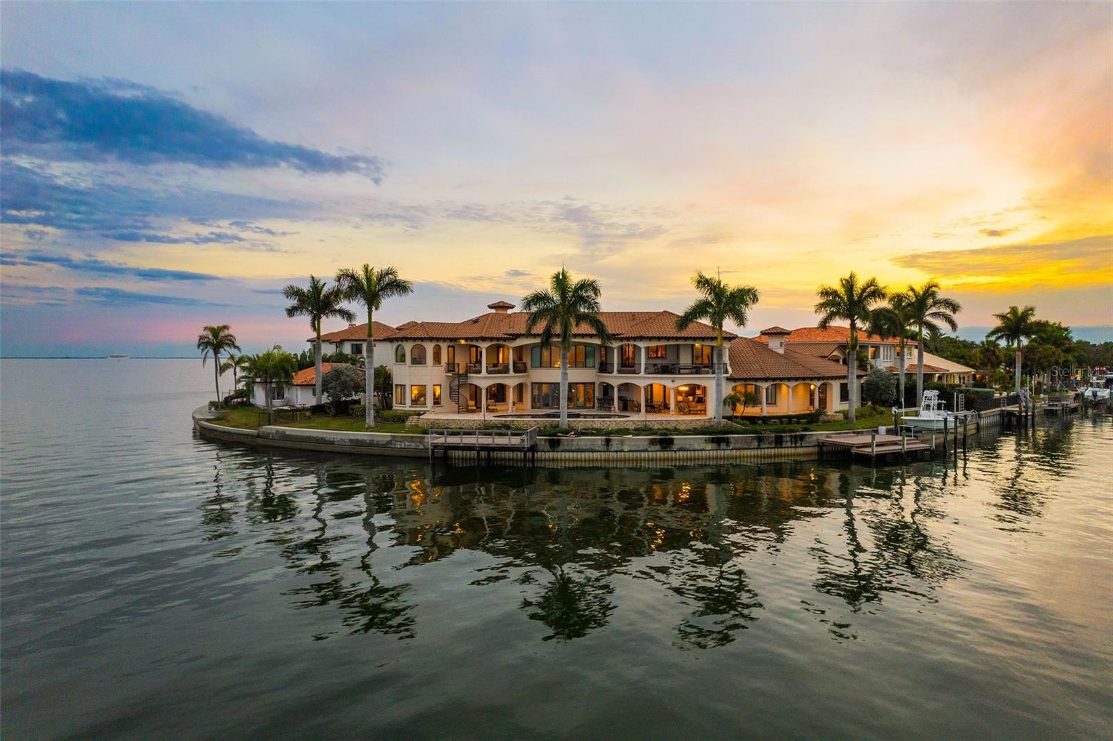 A waterfront masterpiece that has it all! Custom built by Campagna Homes in 2014, this luxury residence boasts soaring high ceilings in just under 8,000 square feet and is situated on two lots with direct access to the open waters of Tampa Bay. The main home features 5 bedrooms, 6.5 bathrooms, and several flex places including an office, a gym, a study, and game room complete with wet bar. A spacious family room for gathering sits just off the main kitchen with its entertainers’ must haves like a butler’s pantry, walk in pantry, and full catering kitchen. The formal dining room with built-in buffet is crowned with a gorgeous Swarovski crystal chandelier and two matching sconces to cast that perfect dinner-time-glow. Just after dinner, usher your guests to the complimentary formal living room to show off the cathedral ceilings and gas fireplace. This spectacular home features the convenience of an elevator as well as the luxury of a sizable 400-bottle wine cellar and serving bar off of the formal dining room. A split 4-car garage comes with a second floor in-law suite with kitchenette and full bath, adding almost 700 square feet to this already abundant home. Inside, you’ll enjoy panoramic water views from nearly every room in the house. Then step outside and take advantage of an extensive outdoor living space with kitchen, fireplace, and a sparkling, saltwater pool with spa. You can also take in all the outdoor beauty this home has to offer from your balconies. You’ll never need to leave, but if you choose to take a sunset cruise, you can hop in a boat from one of your two docks, complete with a boat-lift and jet ski launch. The primary bedroom wing has a groin ceiling entry, custom millwork and, like much of this home, breathtaking views. Unwind in the relaxing primary bathroom with soaking tub, walk through shower, and his and her walk-in closets. The main living and entertaining areas are downstairs with secondary bedrooms, each with its own en-suite bathroom and walk in closet, a bonus living space, custom workspace, and huge outdoor balcony, located upstairs. Stay home and experience the best of Venetian Isles living or travel a few minutes (by boat or car) to St. Petersburg’s finest shopping, dining, and downtown attractions. With quick, convenient access to Tampa International Airport and only 15 miles to our world renowned St Pete Beach, you’re never far from a good time.