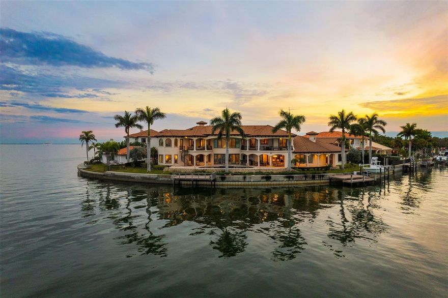 A waterfront masterpiece that has it all! Custom built by Campagna Homes in 2014, this luxury residence boasts soaring high ceilings in just under 8,000 square feet and is situated on two lots with direct access to the open waters of Tampa Bay. The main  home features 5 bedrooms, 6.5 bathrooms, and several flex places including an office, a gym, a study, and game room complete with wet bar. A spacious family room for gathering sits just off the main kitchen with its entertainers’ must haves like a butler’s pantry, walk in pantry, and full catering kitchen. The formal dining room with built-in buffet is crowned with a gorgeous Swarovski crystal chandelier and two matching sconces to cast that perfect dinner-time-glow.  Just after dinner, usher your guests to the complimentary formal living room to show off the cathedral ceilings and gas fireplace. This spectacular home features the convenience of an elevator as well as the luxury of a sizable 400-bottle wine cellar and serving bar off of the formal dining room. A split 4-car garage comes with a second floor in-law suite with kitchenette and full bath, adding almost 700 square feet to this already abundant home. Inside, you’ll enjoy panoramic water views from nearly every room in the house.  Then step outside and take advantage of an extensive outdoor living space with kitchen, fireplace, and a sparkling, saltwater pool with spa.  You can also take in all the outdoor beauty this home has to offer from your balconies. You’ll never need to leave, but if you choose to take a sunset cruise, you can hop in a boat from one of your two docks, complete with a boat-lift and jet ski launch. The primary bedroom wing has a groin ceiling entry, custom millwork and, like much of this home, breathtaking views. Unwind in the relaxing primary bathroom with soaking tub, walk through shower, and his and her walk-in closets. The main living and entertaining areas are downstairs with secondary bedrooms, each with its own en-suite bathroom and walk in closet, a bonus living space, custom workspace, and huge outdoor balcony, located upstairs. Stay home and experience the best of Venetian Isles living or travel a few minutes (by boat or car) to St. Petersburg’s finest shopping, dining, and downtown attractions. With quick, convenient access to Tampa International Airport and only 15 miles to our world renowned St Pete Beach, you’re never far from a good time.