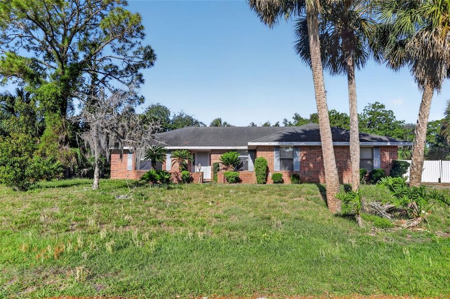 Set on a spacious corner lot framed by towering pines, palms, and lush mature landscaping, this single-story brick home offers standout curb appeal and the kind of setting buyers notice right away. Inside, the layout opens to a generously sized living area with rich wood-look flooring, oversized windows, abundant natural light, and a striking brick fireplace that adds warmth and character. The adjoining dining space is bright and inviting, while the large front room with bay-style windows offers flexible space for dining, office, sitting room, or creative use. Sliding glass doors connect the main living space to the screened lanai and pool area, creating an easy indoor-outdoor flow that is ideal for relaxing or entertaining. Outside, the oversized homesite, extended driveway, privacy fencing, and mature greenery create a private, tucked-away feel with room to enjoy the Florida lifestyle. A rare opportunity to own a home with timeless brick architecture, spacious living areas, a pool, and an impressive lot in an established Deltona setting.