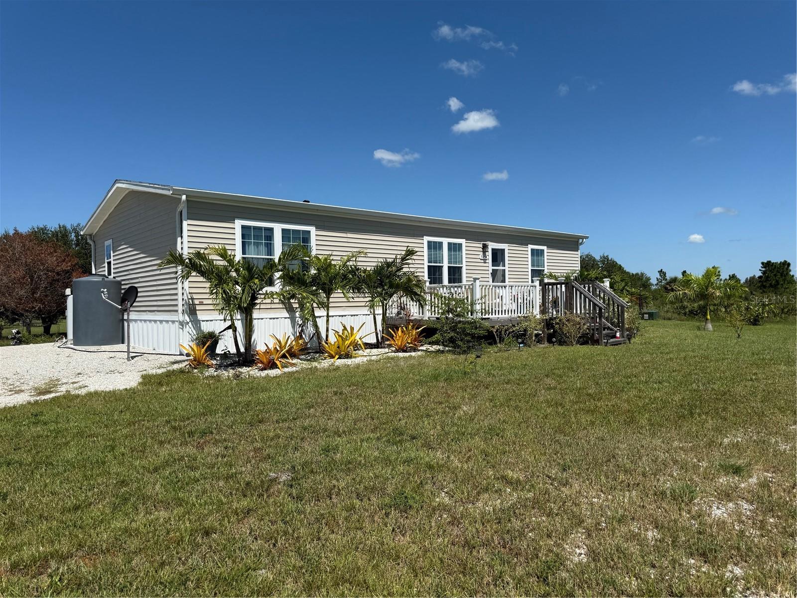 LIVE OUT IN THE COUNTRY ON THIS PEACEFUL, PRIVATE, MANICURED 5 ACRES OF AGRICULTURAL ZONED LAND IN GOLDEN RANCHES, WHICH IS LOCATED ON THE HIGH PLAIN PRAIRIE OF CHARLOTTE COUNTY WITH 60' ELEVATION. The gated, winding road into the property leads you to a pond outside the beautiful manufactured home built in 2023 with 1404' under a/c, which includes 3 bedrooms, 2 bathrooms & a 24x42 RV carport. Home features a leaded glass front door, great room floorplan, split bedrooms, higher ceilings, crown molding, luxury vinyl flooring, kitchen with an island, lots of cabinets & counter space, wall mount range hood exhaust fan, walk in closet pantry, mud/laundry room with storage cabinets, a 12x20 front deck overlooking the pond & 12x20 back deck with a pergola for shade in the afternoon. You have a view of sunrises from the front deck & sunsets from the back deck & an excellent view of the stars at night. Also, sitting on the decks you have the occasional deer, wild turkey & other wildlife wandering thru the land that makes living in the country exciting. There is a new state-of-the-art Whole House R/O system with large water storage tank & underground electric. The driveway leads you towards the back of the land to the RV Carport & the 40' shipping container that has been framed out for a workshop, 2 sheds & a fenced garden area. There are solar panels on a platform that supply electric to the shed & shipping container for a/c, lights & a freezer in one of the sheds. The land is fenced in the front & back, has large oak trees & feels like you are in a park setting. There are no deed restrictions but the zoning allows only 1 home on 5 acres & Horses, dogs, chickens, etc. Access thru the subdivision is on privately maintained marl/sand roads with ditching. Best way to get to the property is down Bermont Road to Eugene Drive, turn onto Eugene & the address will be on the left side of the road. You will be pleasantly surprised with the beauty of the land & home.