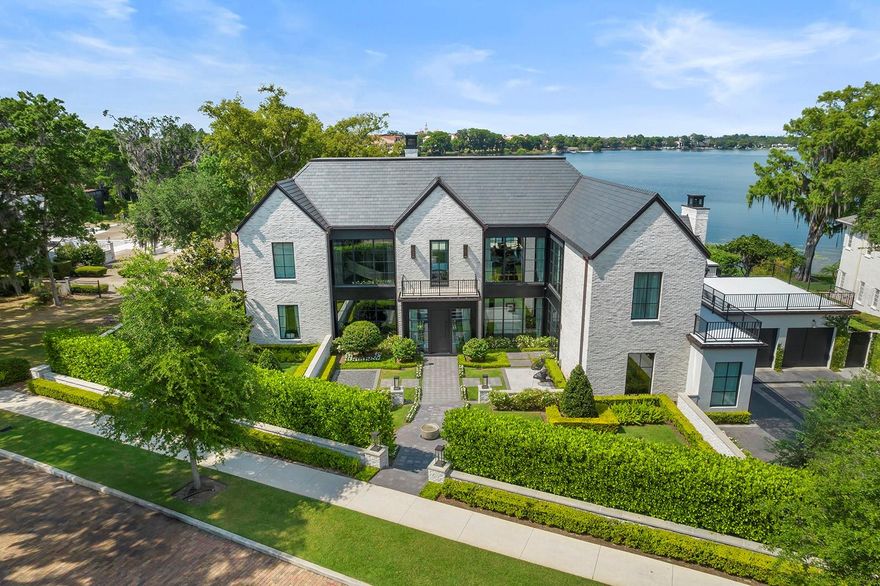 Experience luxury living at its finest with this custom-built masterpiece on the shores of Lake Virginia, proudly crafted by the renowned Phil Kean Design Group. Boasting five or six bedrooms, six full baths, and two half baths (plus library/office, second office, loft and lounge area, exercise room, theatre, bonus/flex room and lots of storage) sprawled across 8,188 heated square feet over three levels (includes high-quality residential elevator), every detail of this home exudes sophistication and elegance. Step through the grand entrance adorned with a custom steel front door from Cantera, where natural marble stone flooring leads you into a space illuminated by art lighting from Troy Lighting and picturesque views directly toward Rollins College Chapel. The wood-paneled walls and ceiling design perfectly complement the custom three-story Alan Mizrahi chandelier, setting the tone for opulent living. Entertain guests in the formal sitting room, complete with a custom Nero marble fireplace and a breathtaking 60" Alora chandelier. Eurowall 14-foot full collapsing doors seamlessly merge indoor and outdoor living spaces, while the kitchen beckons with Plato cabinetry, an Italian 60-inch range, and 4 slabs of Calacatta Italian marble. The double island, featuring countertops by Grothouse, is a chef's dream, accompanied by amenities like the Amuneal wine cabinet and Dacor full-height wine refrigerator. Relax in the family room under vaulted ceilings, where a 16-foot Eurowall opens to reveal views of the serene outdoors. A custom Nero Marquina marble fireplace adds warmth and charm, while automated draperies offer convenience at your fingertips. Retreat to the primary suite, complete with a beverage center and separate laundry room, before indulging in the luxurious primary bath featuring a bateau cast iron tub imported from London and heated floors. Additional bedrooms, all ensuite with walk-in closets, provide comfort and privacy for family and guests alike. Stay active in the fitness room equipped with wall-to-wall rubber gym flooring and a fully equipped "Mr. Steam" steam room. For entertainment, head to the third-floor theater boasting a 120-inch screen with a Sony projector and Triad surround sound speakers. Outside, professional hardscape and landscape design by Corey Mills and Signature Landscape create a picturesque backdrop for outdoor living. Enjoy 148 feet of lake frontage with seawall spanning property, a renovated boathouse, and a newly installed dock with Trex decking and boat lift. Experience resort-style living with a pool designed and installed by Paradise Pools, featuring knife edge and Infinity edge designs, Pentair equipment with mobile app control, and an outdoor kitchen equipped with DCS appliances, Sunbrite television, and more. Resting on an elevated (approximately 3/4 acre lot) on Lake Virginia of the Winter Park Chain of Lakes, this exceptional property offers unparalleled luxury and waterfront living. Don't miss the opportunity to make this your own private paradise.