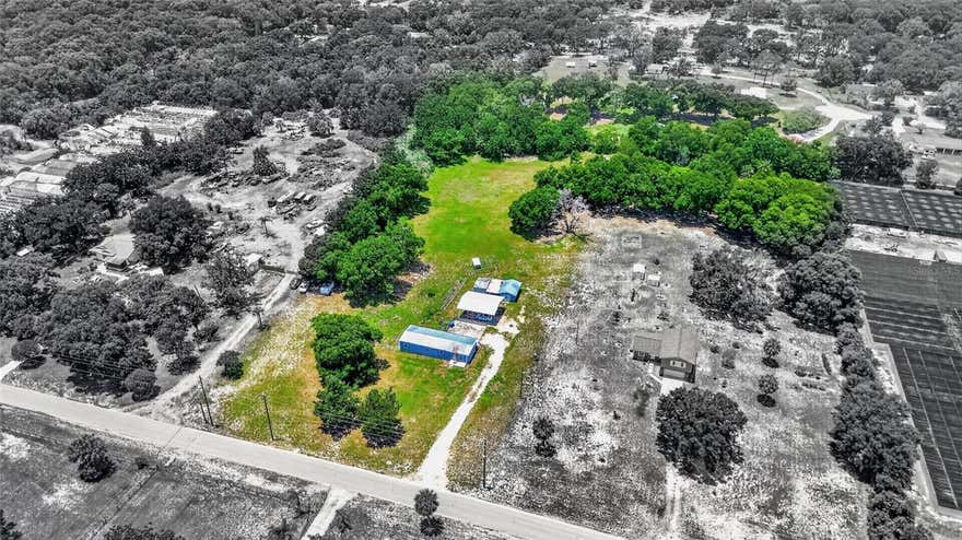 Welcome to your private countryside retreat nestled on 4.28 beautiful acres in the peaceful Mount Dora area. This charming 3-bedroom double-wide home has been updated throughout and offers the perfect blend of comfort, functionality, and rural living. Inside, you’ll find laminate flooring throughout, granite countertops, updated windows and doors, and a brand-new 5-ton AC system providing year-round comfort. Step outside and enjoy the expansive concrete entertaining area with a railing, ideal for relaxing evenings, family gatherings, or hosting guests. The property also features a massive 30x30 covered parking area perfect for RVs, boats, trailers, work equipment, or additional vehicles. A separate block building includes a garage and spacious storage shed, offering plenty of room for tools, hobbies, or workshop space. Zoned Agricultural and located just minutes from downtown Mount Dora and approximately 20 minutes from Orlando, this property offers endless possibilities. Whether you envision creating a homestead, planting a thriving garden, building your own fruit paradise, or simply enjoying the peaceful country lifestyle, this land is ready for your vision. The home could use a little TLC and is being sold as-is, with much of the value found in the beautiful usable acreage. It’s the perfect opportunity to customize into your ideal retirement home, private getaway, or weekend retreat. If you have a green thumb and appreciate open space and privacy, this property is truly a rare find.
For outdoor enthusiasts and fishing lovers, you’ll enjoy being near some of Central Florida’s most popular freshwater fishing and boating destinations, including Lake Apopka, Lake Dora, Lake Eustis, and the renowned Harris Chain of Lakes, known for trophy bass fishing and year-round recreation. Schedule your private showing today and experience the charm, privacy, and endless potential of this countryside paradise.