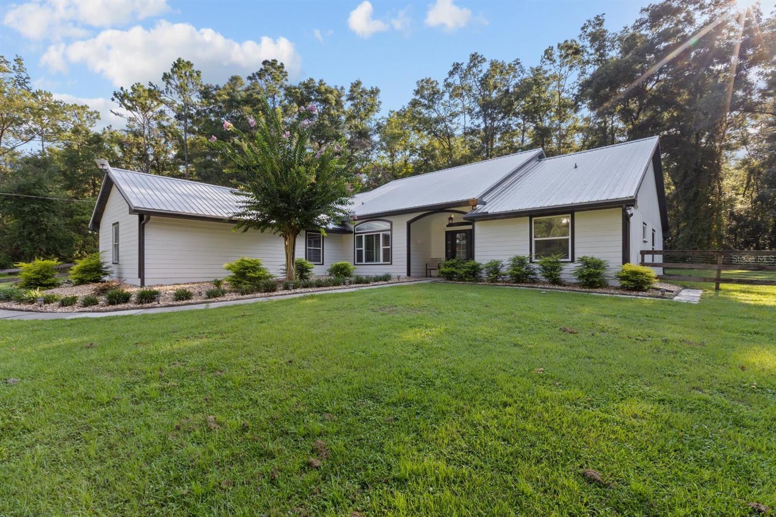 Stunning home with a pool, Barn with an apartment, on 6+ breathtaking acres. 4 bedroom, 2 bath with 3 car garage. Private and secluded in a great NW Gainesville location off of scenic Millhopper Road. Perfect location with easy access to I75, Alachua/High Springs, and the University of Florida. Home offers modern open floor plan with natural light throughout. Kitchen and bathrooms have been updated. Featuring premium vinyl plank flooring throughout, 10 foot ceilings, crown molding, fireplace with wood burning stove insert and plantation shutters. Swimming pool and heated hot tub with fully enclosed lanai. Large 4 stall barn with concrete center and beautiful fenced pastures with pines and hardwoods throughout the property. Perfect for horses or livestock. Barn includes an apartment with 2 bedrooms/1 bath and central heating and air conditioning. Custom chicken coup with run is situated behind the barn. All located at the end of a private lime rock road within a well-maintained community with no HOA. The house is 2,231 square feet and the barn living area is ~ 600 square feet.
**New: HVAC (2024), All New PGT Windows (2025) - Over $25,000. High-end video security system, New Hot Water Heater (2023), New Solar Powered Entry Gate (2024). Starlink Internet system; Board Fence Front Pasture (2024). New Premium Vinyl Plank Flooring (2022). Pool Pump and 250 gal propane Heater (2021). Lawn equipment is excluded from the listing.