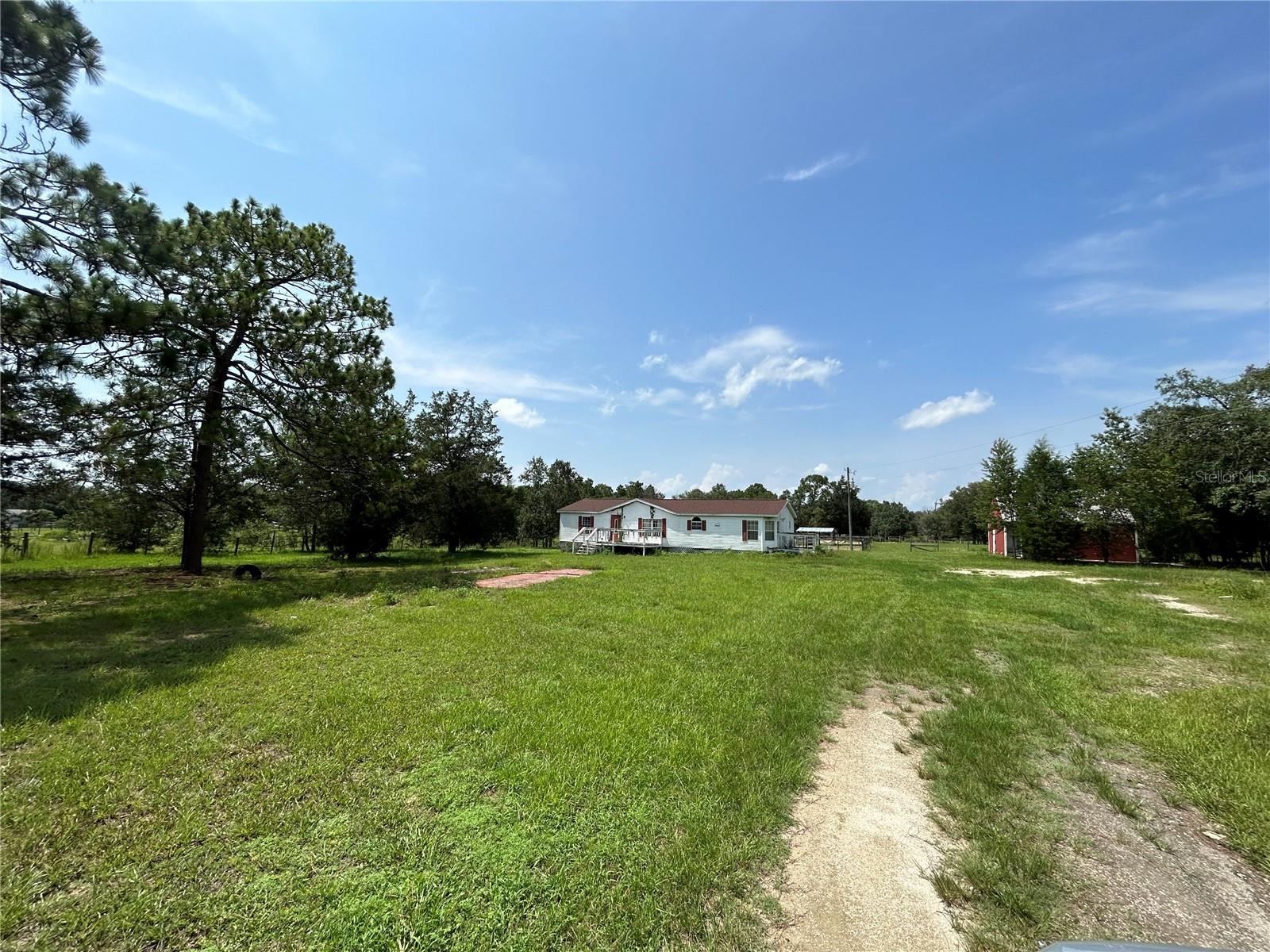 GREAT LOCATION! This small farm with 7.5 acres and paved road frontage is close to all the things outdoor enthusiasts are looking for! Short drive to WEC and Goethe State Forest riding trails. This property features fencing, a solid concrete storage structure with a storm basement, a 24 x 26 pole barn, a fixer upper 1994 double-wide mobile home with 3 bedrooms, 2 baths, and a spacious open floor plan spanning 1,512 sq ft. With vaulted ceilings and lots of potential, this home is ready for your personal touch. With plenty of space for livestock, gardening, and more, you can truly make this farm your own. Located within a convenient drive to Williston, Dunnellon, Ocala, and Gainesville, you'll have easy access to nearby towns while enjoying the peaceful rural setting. Don't miss the opportunity to transform this property into your dream farm. Sold in As-Is condition, Cash or possible owner financing with seller approved down payment and credit check. Schedule a visit today and explore the endless possibilities!