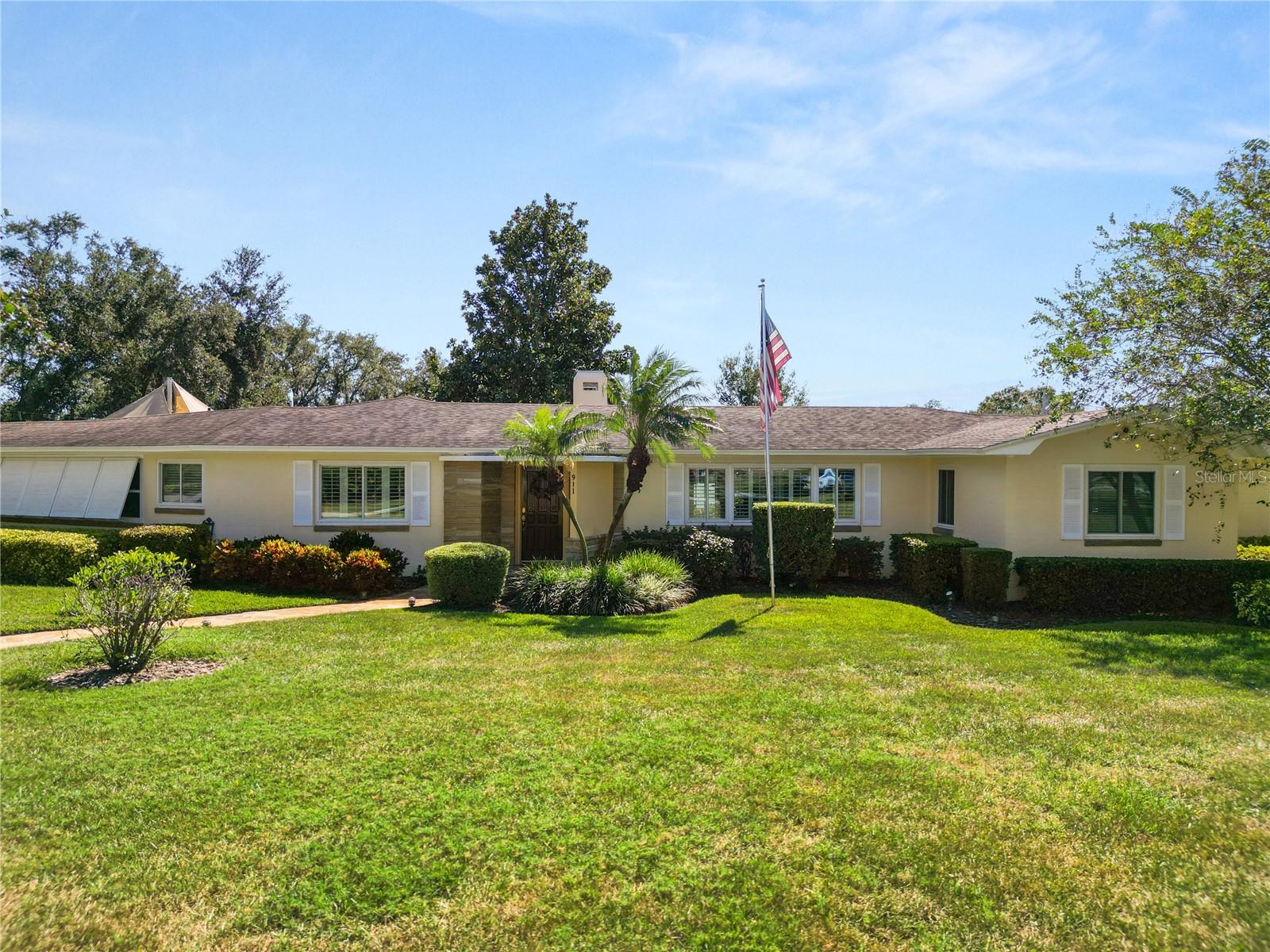Modern Upgrades, Vintage Character — The Best of Both Worlds!  Where Mid-Century Charm Meets Modern Comfort. A Cherished Family Home — Impeccably maintained for Over 50 Years.  This EXQUISITE Mid-Century Modern Beauty situated on .65 Acres.  Discover timeless charm and exceptional care. From the flagstone walkway leading from the street to the front door. Every detail reflects pride in ownership and thoughtful updates over the years. Situated on three spacious lots totaling .65 acres. This 3-bedroom, 2.5-bath home sits on a corner lot, with a fully fenced backyard and lot surrounded by mature landscaping and hedges for privacy. Inside, you’ll find beautiful oak hardwood floors in most of the home, pine flooring in the kitchen and half bath. The two bonus rooms, one off the formal living room has flagstone flooring, and the other bonus room off the kitchen has quarry tile. Both rooms are a peaceful space to unwind.  The kitchen is a focus point with solid wood cabinetry, granite countertops, a built-in China cabinet, and new Samsung stainless-steel appliances (2019). The sunny breakfast area offers panoramic views of the lush backyard through new windows installed in 2016. California Plantation shutters add elegance to the main bedroom, living room, and dining room (installed between 2005–2007). The formal dining room features a charming chair rail. The family room boasts a wood-burning fireplace, built-in shelving, and a wet bar which creates the perfect space for entertaining family and guests, plus a small office.  Recent updates include Roof replaced in 2019, 2 new Air Conditions 2021, Deep irrigation well installed in 2012 (250 ft depth) new windows in living, dining, and main bedroom 2016-2022, The backyard oasis is truly special — featuring a large wooden deck with sunshade sails to protect from UV rays. A serene koi pond featuring waterfall, automatic water refill system and lighting for evening enjoyment. There’s also a custom lattice enclosure with automatic watering, perfect for displaying a staghorn fern or lush plants, with an avocado and mango tree producing delicious fruit. Additional highlights include a spacious laundry room with ample cabinetry, garage with storage room, and a rare reinforced concrete basement (10’ x 20.8’) equipped with shelving on both sides and a sump pump for peace of mind. This extraordinary home blends mid-century design with modern upgrades, creating a warm and welcoming ambiance both inside and out. Come encounter this one-of-a-kind property — where character, quality, and care come together to create your dream home in the heart of Lakeland!  All measurements are approximate and must be verified by buyer.