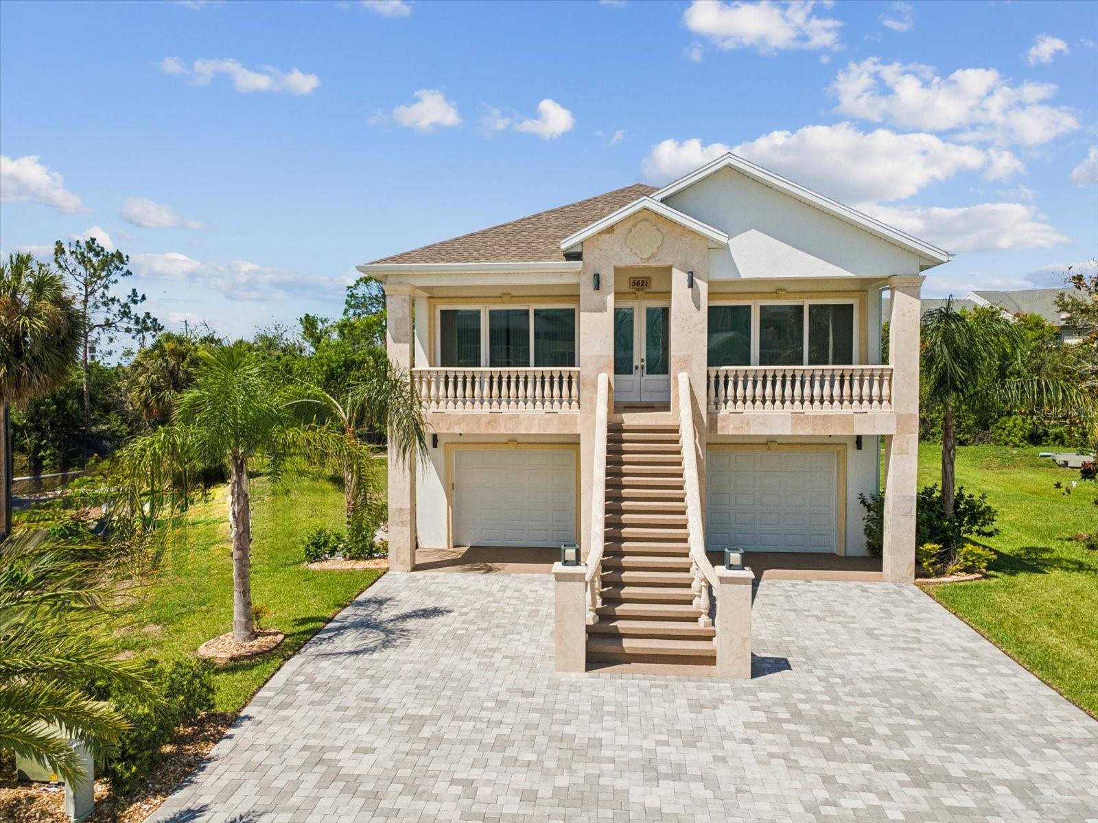 Discover exceptional modern living in this stunning cement stilted home, meticulously built in 2022 to stand strong against floods and hurricanes. Spanning 2,658 sq ft, this stylish residence boasts 4 bedrooms and 3.5 baths, thoughtfully designed to blend comfort and sophistication. The expansive garage, accommodating more than eight vehicles, includes climate and humidity control, plus a fully equipped 16-cabinet Husky workshop. Ideal for car enthusiasts or those with boats and toys, there's ample space for all your needs. Inside, enjoy contemporary elegance highlighted by solid wood cabinetry, luxurious quartz countertops with a waterfall edge, and premium appliances in the gourmet kitchen. The home offers balconies at the main entry and rear, along with an inviting outdoor deck—perfect for entertaining or relaxing. Impressive details include hurricane-impact windows and doors, soaring tray ceilings, tile flooring throughout, generous walk-in closets in every bedroom, and a custom saltwater pool featuring a serene waterfall, making this outstanding home a must-see to truly appreciate all it has to offer. Located in an exclusive gated community, residents have access to premium amenities: a pool and spa, tennis courts, clubhouse, two community boat ramps, and exclusive membership to private beach.