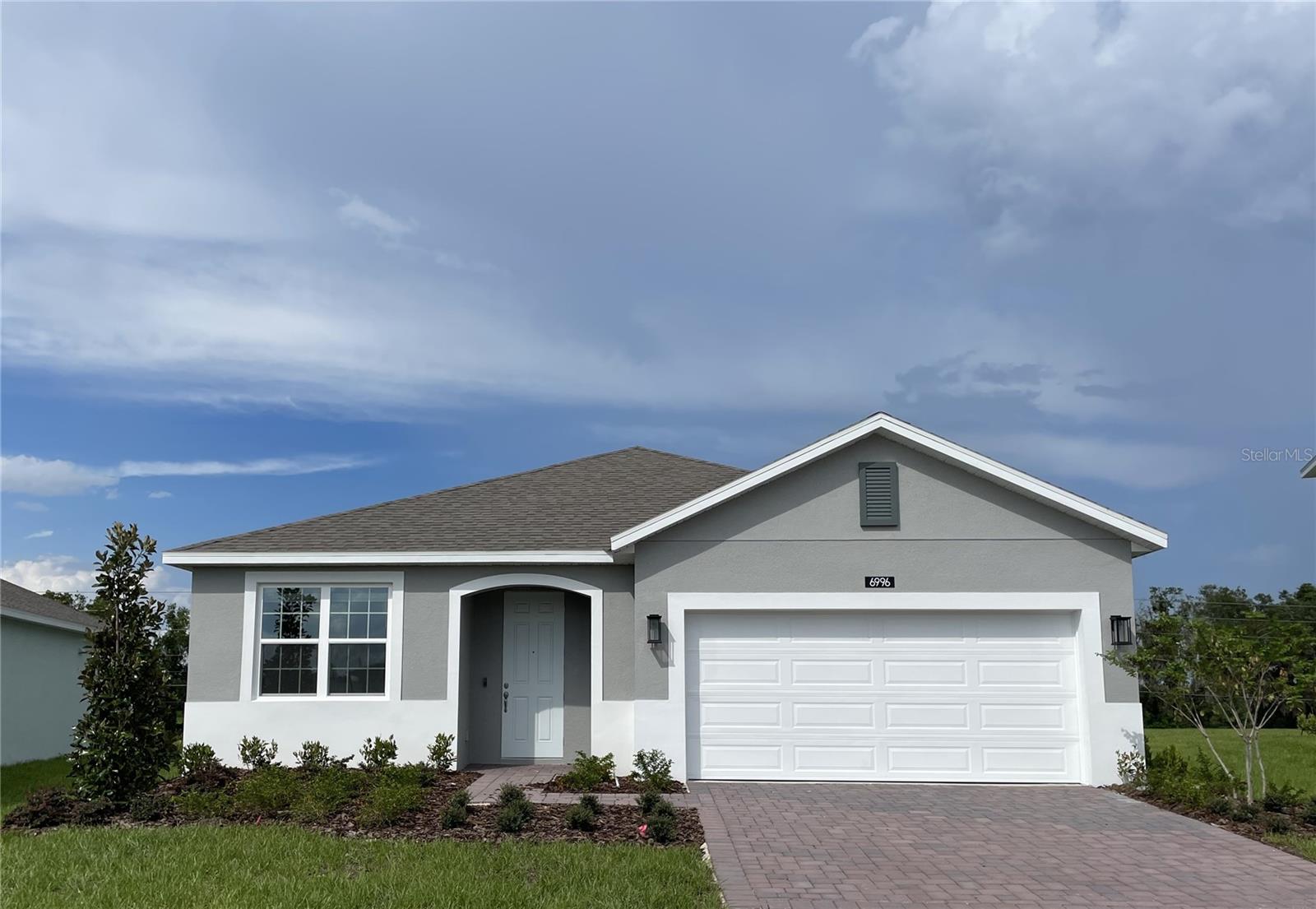 Step into style and comfort with this stunning new home on an oversized homesite featuring an open-concept design, 4 spacious bedrooms, 3 full baths, and a 2-car garage. The expansive Great Room seamlessly flows to a covered rear lanai—ideal for entertaining or enjoying outdoor living with no rear neighbors! Stylish tile flooring enhances the main living areas, while blinds are included throughout for added convenience. The well-appointed kitchen showcases 42" gray cabinets, quartz countertops, a large island, pantry closet, and stainless steel appliances—including refrigerator. Relax in the spacious Primary suite with a luxurious ensuite bath featuring adult-height vanity with dual sinks, shower with wall tile surround, and an oversized walk-in closet. Additional highlights include attractive landscaping, brick paver driveway and lead walk, and a fully equipped laundry room with washer and dryer. This home is truly move-in ready! Community amenities include Resort-style Pool and shaded Playground. Eagletail Landings is located just south of Lake Harris and near some of the best outdoor recreation in the state as well as Lake County's breathtaking chain of lakes and scenic trails, and a thriving downtown area is just a short drive away, along with 2 nearby championship golf courses designed for a challenging and enjoyable day on the greens.