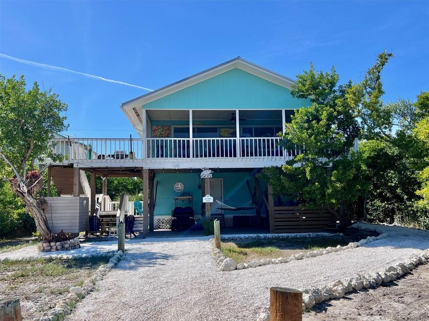 This inviting three-bedroom, two-bathroom home, has an assumable mortgage at 3.18% and is nestled at the end of a quiet cul-de-sac in Gaspar’s Hideaway on Little Gasparilla Island. Accessible only by private boat or water taxi, Little Gasparilla Island is a bridgeless barrier island just off the Cape Haze peninsula, offering a unique sense of seclusion and tranquility. The exterior of the home features a spacious screened-in front porch, perfect for relaxing and enjoying the gentle island breeze. On the side of the house, a large sunny deck provides an ideal spot for outdoor grilling. Additional amenities include a fire pit area and an outdoor shower, enhancing the island lifestyle. Upstairs, the kitchen, living room, and dining area are designed with vaulted ceilings, creating an open and welcoming atmosphere ideal for entertaining guests. The kitchen is equipped with granite countertops, a granite waterfall breakfast bar, solid wood cabinets, stainless-steel appliances, and an attractive blue glass subway tile backsplash. The upstairs bathroom has been updated with a modern vanity and features blue glass tiles in the shower. The home features wood plank look ceramic tile flooring throughout, providing a cohesive and stylish appearance in every room. There are two bedrooms and one bathroom upstairs, while a bonus bedroom and full bathroom are located downstairs. The downstairs storage and laundry room offers plenty of space for storing beach toys, fishing gear, and tools, making it convenient for all your island adventures. Little Gasparilla Island is renowned for its peaceful, friendly atmosphere, free from shops, restaurants, and car traffic. Residents enjoy wandering sandy trails set amid lush tropical foliage, as well as 3 ½ miles of pristine beaches perfect for searching for seashells and sharks’ teeth. Gaspar’s Hideaway provides three community docks on a first-come, first-served basis and deeded beach access for residents. Experience the very best of island living—you may soon find yourself wanting to call this special place home.