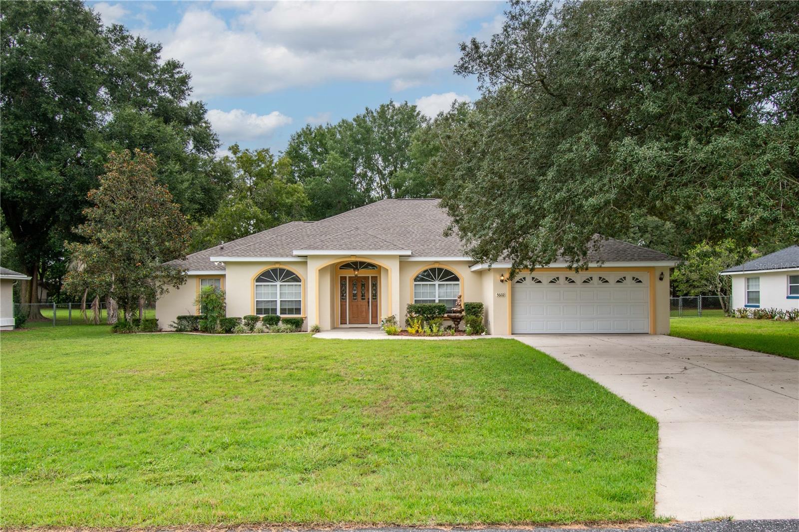 Set on nearly half an acre in Kingsland Country Estates, this 3-bedroom, 2-bath residence offers a generous 2,391 square feet of thoughtfully designed living space. Lovingly maintained and move-in ready, the home balances comfort with functionality within an established HOA community. Tastefully landscaped with plenty of curb-appeal, the home features a covered entryway and a large front yard accented by a grand oak. Inside, tall ceilings, abundant natural light, and a split-bedroom layout create an open, airy flow. The front bedroom just off the foyer makes an ideal guest space or a private home office, while the formal dining room to the other side of the foyer provides a dedicated setting for hosting. At the heart of the home is a spacious living area that features wood-look flooring for both style and durability. The kitchen is designed for those who love to cook, with abundant cabinet and counter space, a gas range with range hood, breakfast bar, and a bright breakfast nook framed by bay windows that overlook the backyard. The primary suite offers a quiet retreat with tray ceilings, direct patio access, and two walk-in closets. Its en-suite bath includes dual sinks, a glass-door shower, and a garden tub for added relaxation. Enjoy Florida’s year-round warm weather in the home’s large screen-enclosed patio, which features a covered space with a ceiling fan, and ample room for a hot tub, barbecue, and seating as desired. The backyard is spacious and open, dotted with mature trees that create a nice, peaceful setting to enjoy. Located just minutes from State Road 200’s shopping, dining, and conveniences, with easy access to I-75 for travel or commuting, this property blends neighborhood living with everyday accessibility. Discover the comfort and convenience waiting for you—schedule your private tour today!