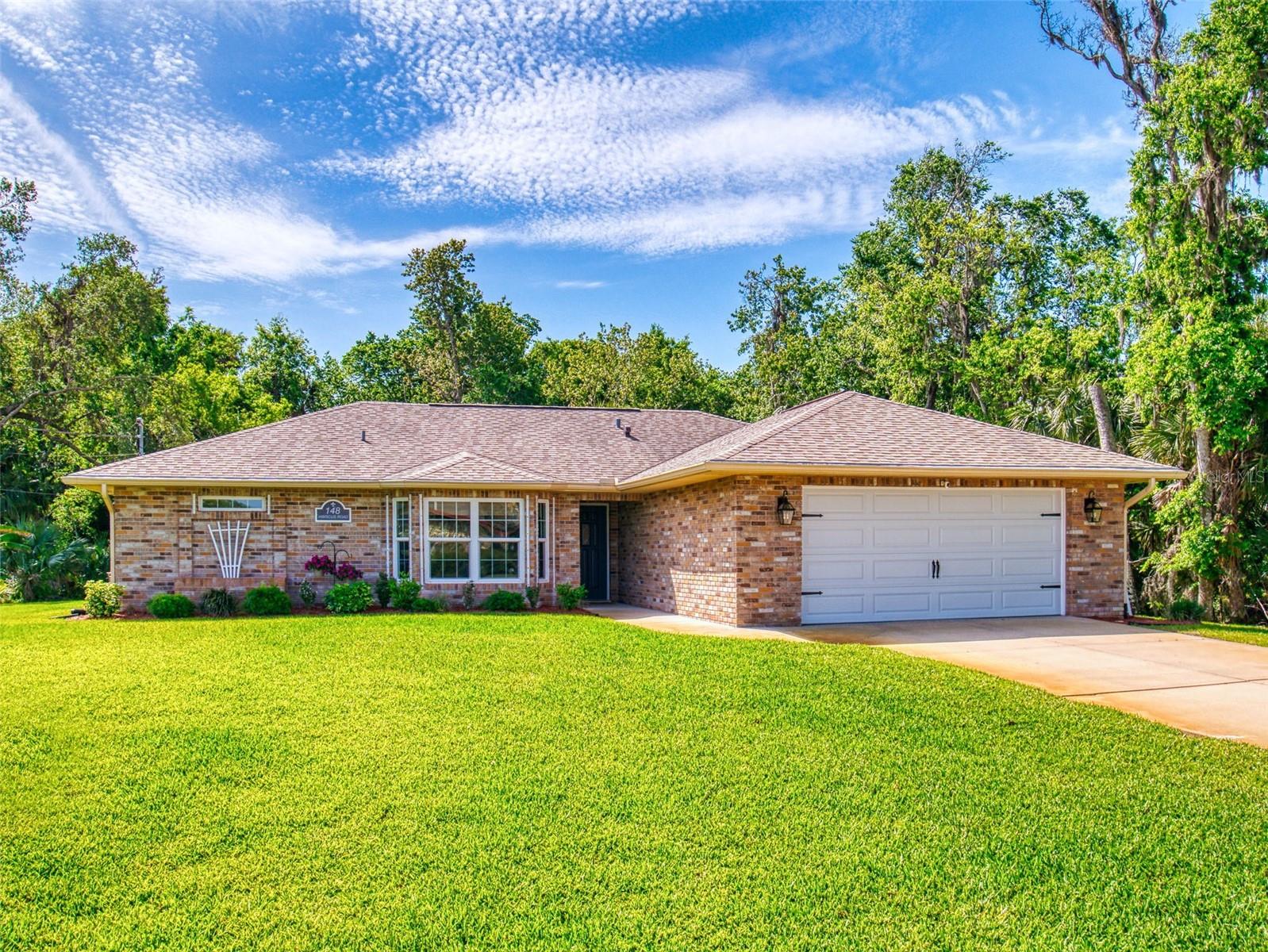 Located in one of the most sought-after neighborhoods in Edgewater, this immaculate custom-built home is move-in ready and blends elegance, comfort, and modern convenience. Offering the perfect balance of coastal and mainland lifestyle, this 4-bedroom, 2-bathroom residence features an open-concept layout designed for everyday living and effortless entertaining. From the moment you step inside, you’ll notice thoughtful craftsmanship throughout—from the rich engineered wood floors to the exposed wood beam accents and elegant lighting fixtures. The heart of the home is an inspiring chef’s kitchen, complete with sparkling stainless steel appliances, stone countertops, custom cabinetry, and a smart, functional design. A cozy eat-in dining area and a breakfast bar seamlessly connect the kitchen to the spacious, sun-filled living room separate dining room and additional family room. Step through the dining area and enter your own outdoor sanctuary: an expansive, covered, screened-in patio that functions as a second living space. Whether you’re sipping drinks at the bar, gathering for dinner, or lounging in the sitting area, this space is bathed in natural light and surrounded by lush, mature native foliage—ideal for year-round enjoyment. The private Owner’s Suite offers direct access to the patio and serves as a serene retreat. It features a luxurious en-suite bath with dual sinks, a large walk-in shower with bench seating, a separate water closet, and a spacious walk-in closet with an adjacent changing area. A whole house generator ensures continuous comfort and security while the new HVAC (2023) provides the cooling necessary for those hot FL days. Other features include hurricane windows (2021) and roof replaced in 2017. Additional highlights include a cozy fireplace, indoor laundry room, an oversized garage with a built-in workbench and custom cabinetry, cabinets making it an ideal place for fixing, storing, or tinkering all in a premium location just moments from the brackish waters of the Indian River—perfect for nature lovers and outdoor enthusiasts. This home is a hidden gem and truly a must-see!