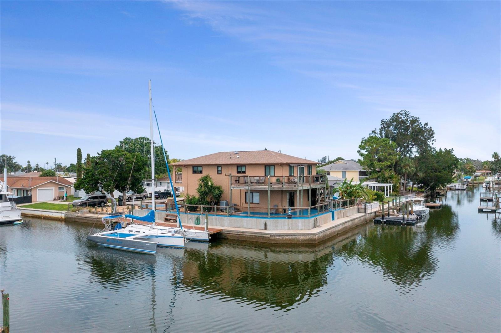 Welcome to Hudson Beach Estates! This beautifully maintained waterfront home offers the perfect combination of peaceful coastal living and convenient access to amenities, making it ideal as a full-time residence, second home, or vacation getaway. Featuring 3 bedrooms, 2.5 bathrooms, and an oversized 2-car garage with built-in cabinetry and storage, this elevated two-story home provides spacious and flexible living. Enjoy scenic water views from the wraparound porch and upper-level balcony, perfect for relaxing or entertaining. Downstairs, you'll find a large living area complete with a half bath and a separate bedroom — ideal for guest quarters or a home office. Upstairs, the open living and dining area is filled with natural light, with sliding glass doors leading out to the expansive porch, complete with an automatic retractable canopy. The kitchen is well-appointed with solid surface countertops, stainless steel appliances, and generous cabinet storage. The primary suite features a fully updated en suite bathroom, a walk-in closet, and sliding glass doors opening to the upper balcony with beautiful water views. A second upstairs bedroom also includes a walk-in closet and access to the balcony. For boating and water sports enthusiasts, this home includes a 52-foot dock, a 176-foot wraparound seawall, and a seawall-mounted davit crane — perfect for launching kayaks, canoes, or jet skis. The deep-water canal offers direct access to the Gulf of Mexico with no fixed bridges. Additional updates include: Roof (2016) Water heater (2017) Upstairs A/C (2016) Downstairs A/C (2022) Located near beaches, dining, shopping, and marinas — don't miss this opportunity to live the Florida waterfront lifestyle. Schedule your private showing today!