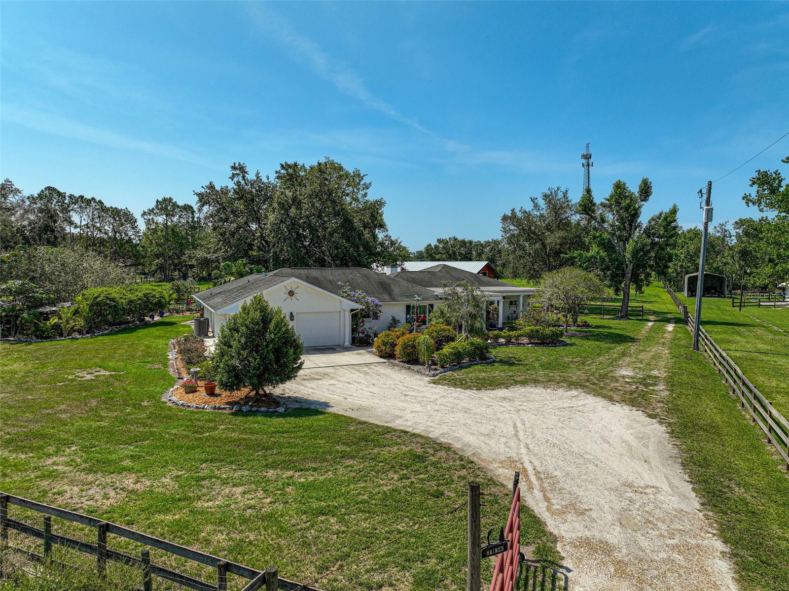 A Slice of Old Florida Charm, Luxurious 5-Acre Equestrian Retreat with Barn & Scenic Views! Escape to a lifestyle of serenity, space & timeless southern charm in this exceptional estate. Perfectly positioned just minutes from Lakewood Ranch yet tucked away on a quiet country road, this custom-built home offers the ultimate blend of privacy, elegance & freedom, w/ no HOA & over five acres of fully fenced land to call your own. From the moment you arrive, the home’s charm is undeniable, welcoming you with an expansive covered front porch adorned w/ stately columns & elegant slate tile underfoot. This inviting space sets the tone for the entire property, offering a peaceful place to sip your morning coffee or enjoy quiet evenings surrounded by lush landscaping & flowering accents. Designed for both comfort + function, the residence spans 2,543 sqft & features 3 bedrooms, 3 full bathrooms & a thoughtful split floor plan that offers flexibility for families, guests, or multigenerational living. Step inside to find light-filled living spaces with vaulted ceilings, flowing tile floors in the kitchen, dining & utility areas & wood-look tile running through the living room & guest wing. The living room is warm & inviting with rich wood-paneled ceilings, a cozy brick wood burning fireplace, elegant upgraded fixtures & beautiful crown molding, details that elevate the sense of classic Southern refinement. At the heart of the home, the chef’s kitchen is a dream with solid wood cabinetry, stainless steel appliances, and additional counter space are perfect for prepping meals or gathering with friends. A charming dinette just off the kitchen offers French doors that open to the oversized screened lanai, while the formal dining room, with its own crown molding, sets the tone for more elegant occasions. The primary suite is a true retreat, w/ French doors to the lanai, walk-in closet & a spa-like en-suite bathroom featuring a jetted tub, dual vanities & a separate shower. A split guest suite functions beautifully as a second primary, w/ its own sliding glass door to the patio, a walk-in closet & a recently updated en-suite bathroom w/ a new vanity, fixtures, chair rail molding, shiplap accents & a beautifully tiled shower. The third bedroom is ideal as a flex space, office, or den & sits adjacent to a fully updated bathroom w/ shiplap & new vanity. All windows + doors have been upgraded to hurricane-rated impact glass including both the living room & guest suite sliders. These open to one of the home’s standout features: a stunning screened paver patio. Partially covered & surrounded by lush views, this relaxing outdoor haven is perfect for enjoying morning coffee, entertaining guests, or simply taking in the beauty of your land. Outside, the property comes alive with opportunity. A 59’ x 56’, 4-stall (12x12 each) center-aisle barn w/ 12x24 tac room + workshop, electric & water is ideal for horses & the cross-fenced pastures, shaded by mature oak trees, create a picturesque & functional setting for a hobby farm or equestrian use. Raised garden beds, butterfly gardens, vibrant landscaping & whimsical sitting areas add to the charm & create peaceful spaces to unwind. W/ no deed restrictions & quick access to I-75, top-rated schools & all the amenities of Lakewood Ranch + East Bradenton, this home is a rare find. Beautifully realized, meticulously maintained & move-in ready. This isn’t just a home, it’s a lifestyle, ready to be enjoyed for years to come!
