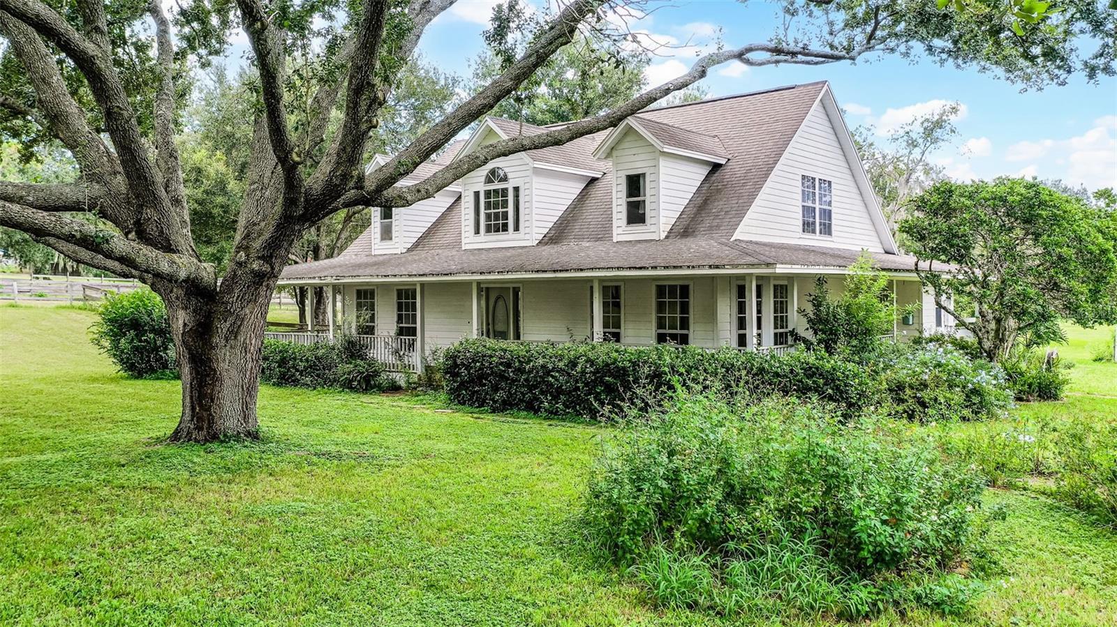 Welcome to your own private equestrian paradise, where rural tranquility meets modern convenience on this stunning 5-acre property. This gorgeous home w/its inviting wrap-around porch sits high and dry, offering the perfect blend of country living and accessibility to Central Florida's attractions. The heart of this property is the impressive 36x36 three-stall barn, complete w/water and electric service, a dedicated tack room and office space, convenient wash rack, and a center concrete aisle for functionality. Whether you're bringing your beloved horses to enjoy the multiple fenced and cross-fenced areas or simply appreciating these majestic animals from afar, this setup provides everything an equestrian enthusiast could desire. The home features a brand new roof installed in September 2025, ensuring years of worry-free protection for your investment. Inside the beautifully designed home, you'll discover a thoughtful layout that maximizes both comfort and views. The dramatic two-story cathedral ceiling in the living room creates an impressive sense of space while offering stunning vistas of the screened rear porch, pastures, and barn beyond. The primary bedroom conveniently located on the main floor includes a spacious walk-in closet and a bathroom featuring both a relaxing soaking tub and separate shower. Adjacent to the primary suite, an attached office, den, or potential nursery overlooks the rear yard and barn, providing the perfect space for work or relaxation while keeping an eye on your property.
The home's recent upgrades ensure modern efficiency and peace of mind, w/both air conditioning units and the hot water heater being only 1 year old. The brand new roof, while not yet reflected in current photos, adds significant value and protection to your investment.
Beyond the exceptional facilities, this property offers an enchanting connection to nature that's increasingly rare. The same family of turkeys and majestic sandhill cranes return seasonally with their babies, creating delightful wildlife viewing opportunities, while hawks and owls provide fascinating birdwatching experiences. The expansive night skies, unmarred by city lights, offer spectacular stargazing. Despite feeling worlds away from the hustle and bustle, convenience remains paramount. You're just 20 minutes from grocery stores, shopping centers, theater, and restaurants, ensuring easy access to daily necessities and entertainment. For broader adventures, Orlando International Airport, Disney World, Universal Studios, and all major Central Florida attractions are less than an hour away, along with extensive shopping at huge regional malls.
This exceptional property offers the increasingly rare opportunity to own significant acreage w/equestrian facilities while maintaining reasonable access to city amenities. Whether you're an experienced horse owner, someone dreaming of entering the equestrian world, or simply seeking a peaceful retreat with room to breathe, this property delivers on every front. The combination of practical facilities, natural beauty, wildlife viewing opportunities, and strategic location creates a truly unique offering that satisfies both practical needs and dreams of rural living. Come experience the magic of country living where every sunrise brings new possibilities and every sunset provides a perfect end to the day, all while knowing that modern conveniences and world-class attractions remain easily accessible whenever desired.