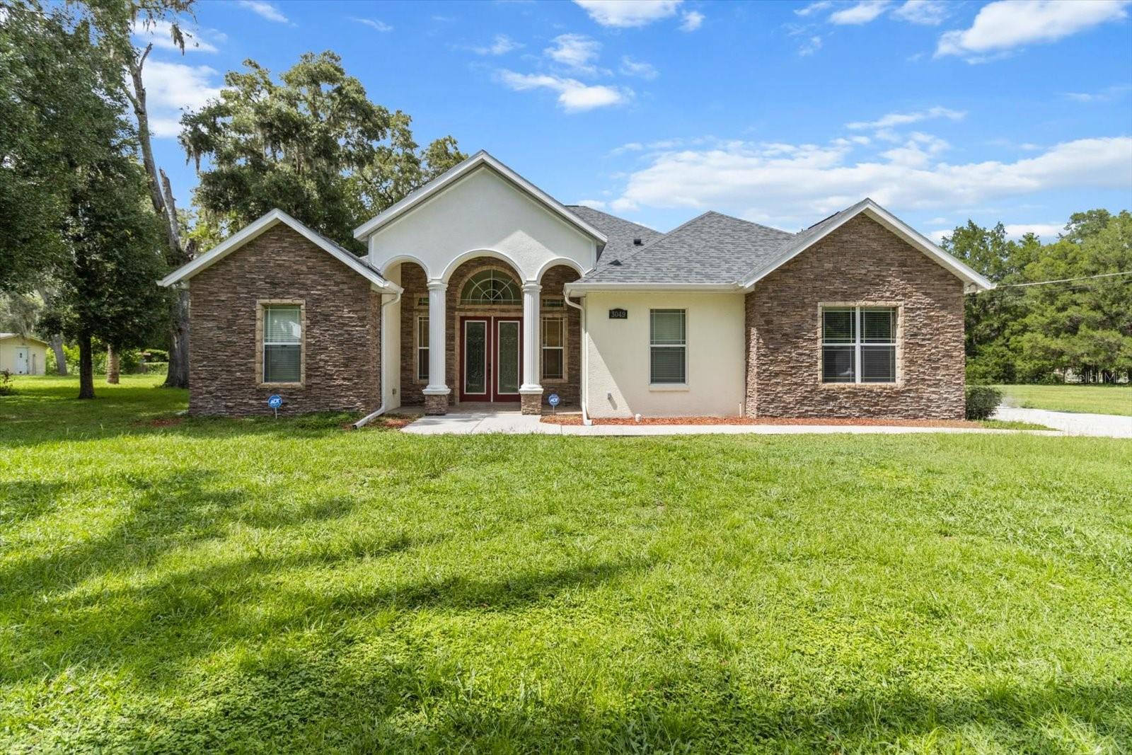 OH, THE SPLENDOR OF IT ALL! This impressively large 3,264 sqft home with 3 bedrooms, 2 baths plus office is a true masterpiece with a classical, traditional warmth bounding from room to room throughout the sprawling floor plan. Mature shade trees spread across 3 homesites, totaling 1.74 acres making the curb appeal undeniable and the possibilities endless. Stacked stone adorns the front elevation, while the entry makes your expectations soar! The home’s interior will not disappoint with the high ceilings that add depth and visual interest, the ample windows that bring the light and sun that only Florida can bring, the arch doorways and 8’ doors trimmed with fluted casings that add character and elegance, the decorative, lighted built ins nestled in the walls that allow your own personal flair, and last but not least, the architectural columns that add that touch of class. The gourmet kitchen is a chef’s desire, with the 42” maple cabinets with crown molding, African granite countertops, center island, breakfast bar and stainless-steel appliances that include a built-in microwave and wall oven with warmer drawer. Oh, I almost forgot the GAS COOKTOP WITH STACKED STONE GROTTO! The stacked stone theme continues into the living room with the full wall gas fireplace with hearth, mantel and arched wall niche beautifully placed between 2 arched built-ins with cabinetry, shelves and lighting. A 4-panel stacking slider opens to the covered lanai. The extravagance continues in the master bedroom which features a tray ceiling, sitting area, French door to the lanai, 2 large walk-in closets and an ensuite with dual sinks, built in make-up desk, walk in tiled shower w/ corner seat, separate garden tub, water closet and linen closet. Roof in 2023. Security system and propane tank are currently leased. A 2 ½ car detached garage and a 2 STORY OUTBUILDING with electric, air and outdoor carpeting are a major plus! Perfectly located less than ¼ mile off 2 of the county’s major road connectors, CR491 and SR 44, for convenience. Bonus: Just 5 minutes to hop on the Suncoast Pkwy, then about an hour to Tampa for shopping, dining, recreational activities & nightlife. Or head 15 minutes west to Crystal River to enjoy boating, scalloping and the only place to SWIM WITH THE MANATEES! A FREE 1-YR HOME WARRANTY for PEACE of MIND is OFFERED to the Buyer!